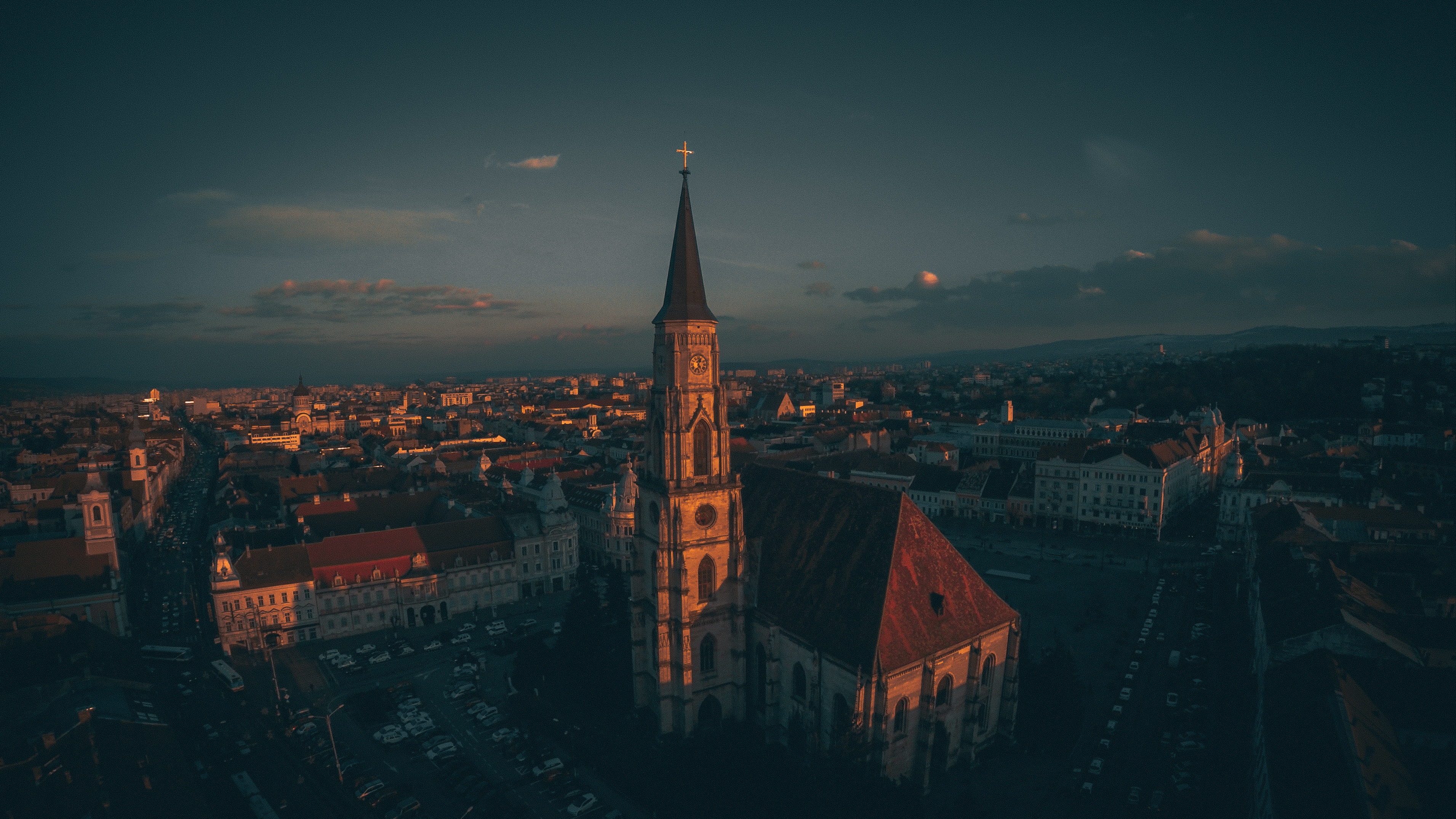 Drone view of a church spire in a city at sunset HD Wallpaper