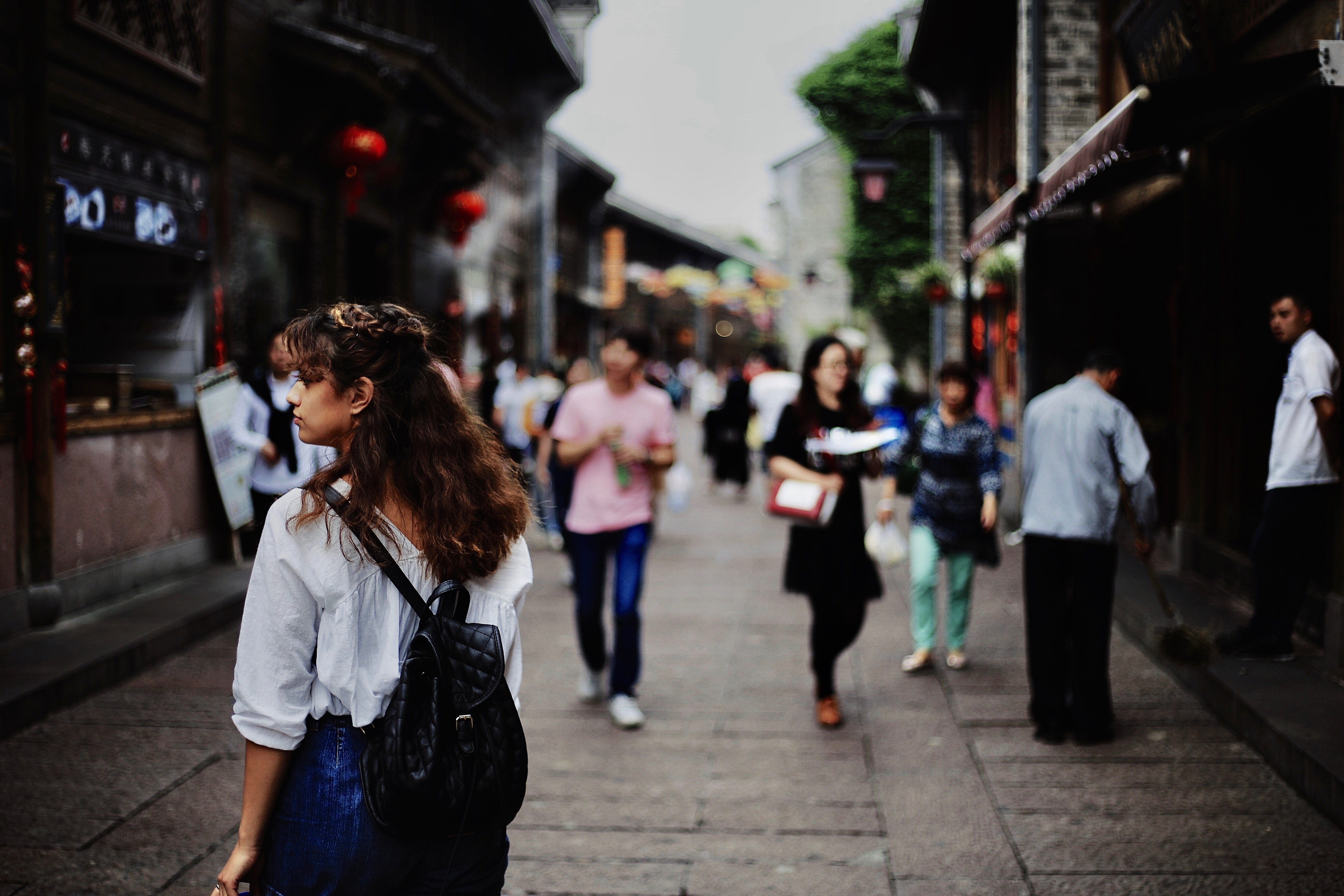 Woman with backpack walking down a street in China HD Wallpaper