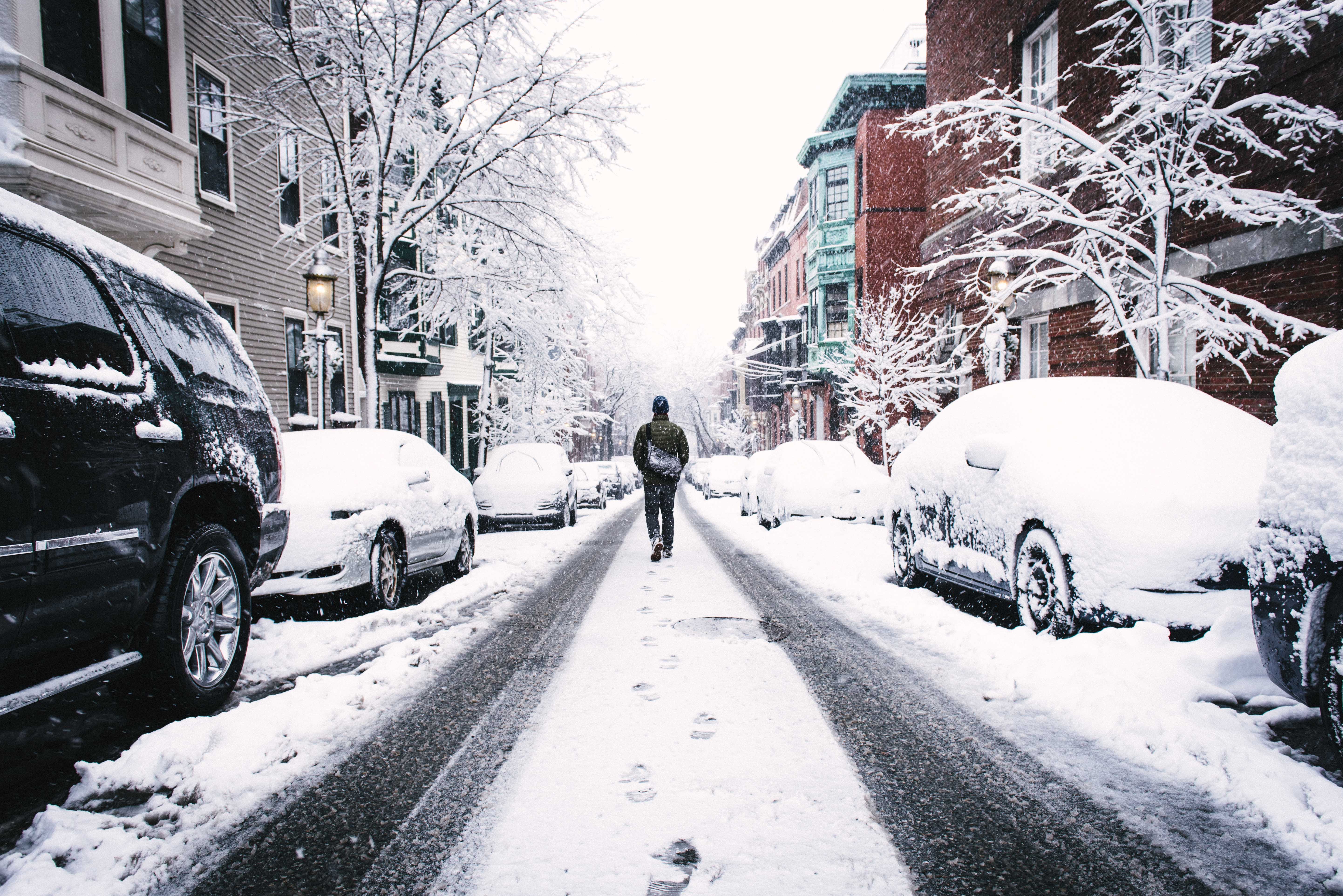 Man walking down a snowy city street HD Wallpaper