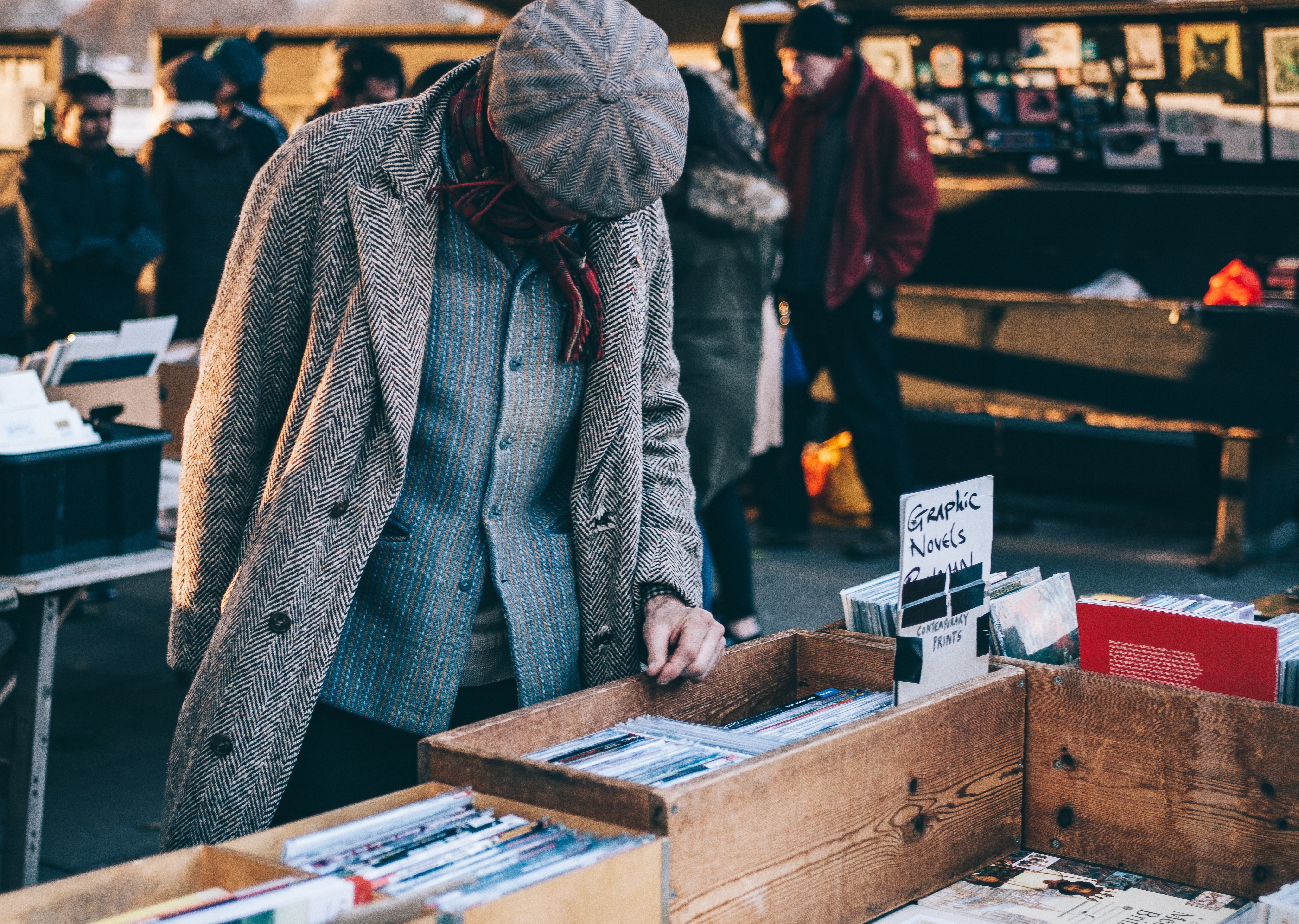 Man browsing graphic novels at an outdoor market HD Wallpaper