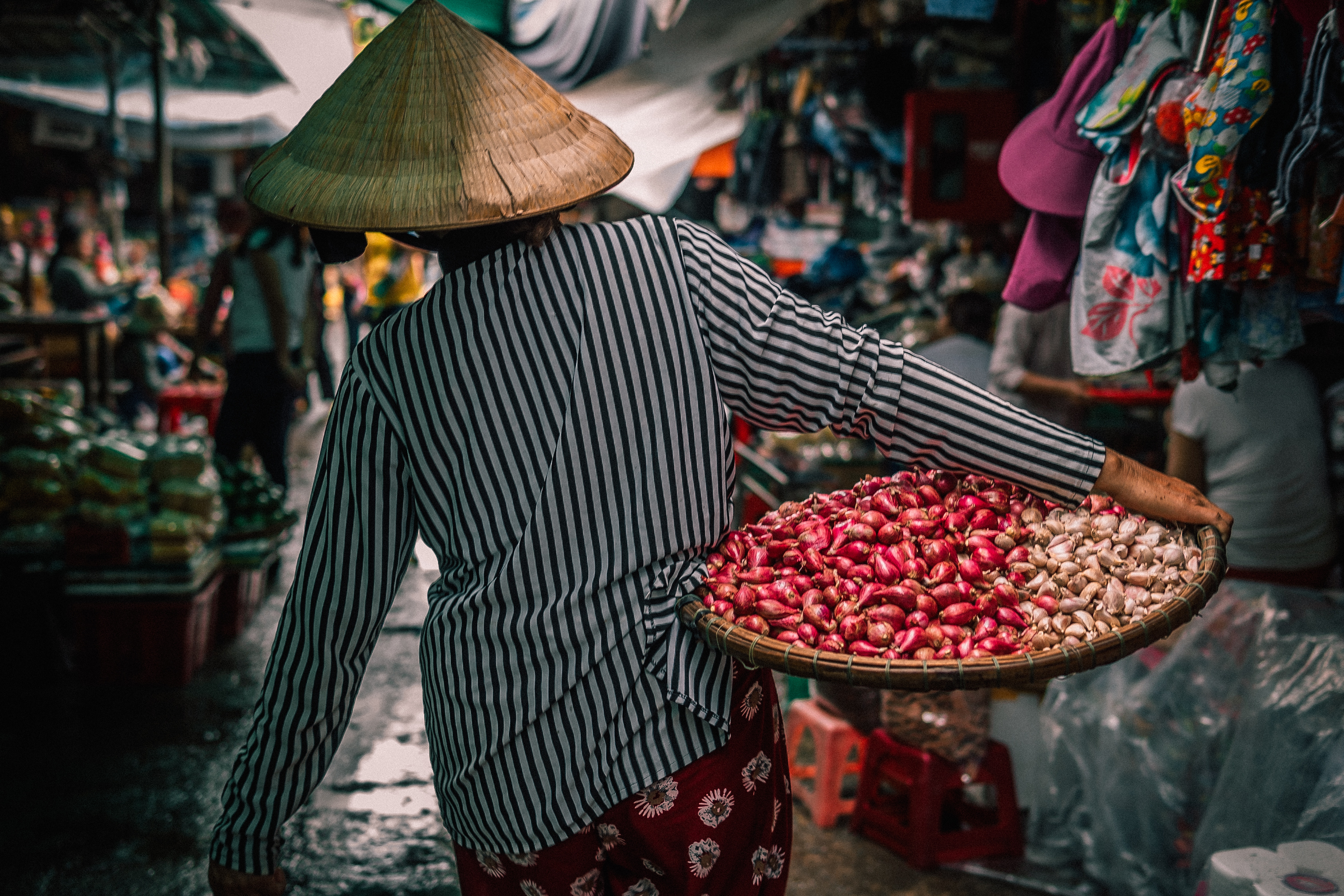 Person wearing a conical hat carrying produce at a market HD Wallpaper