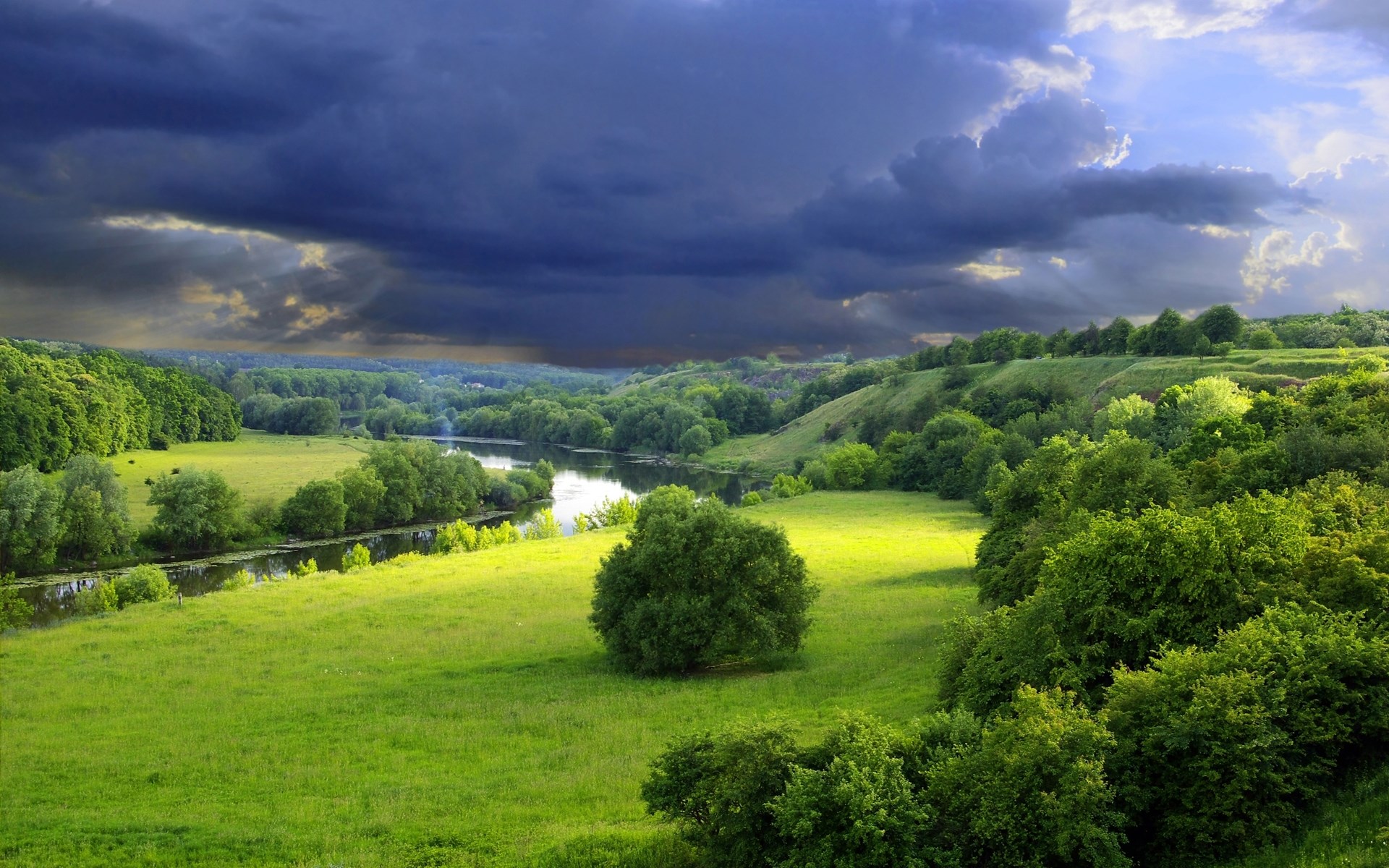 Stormy sky over a green river valley landscape HD Wallpaper