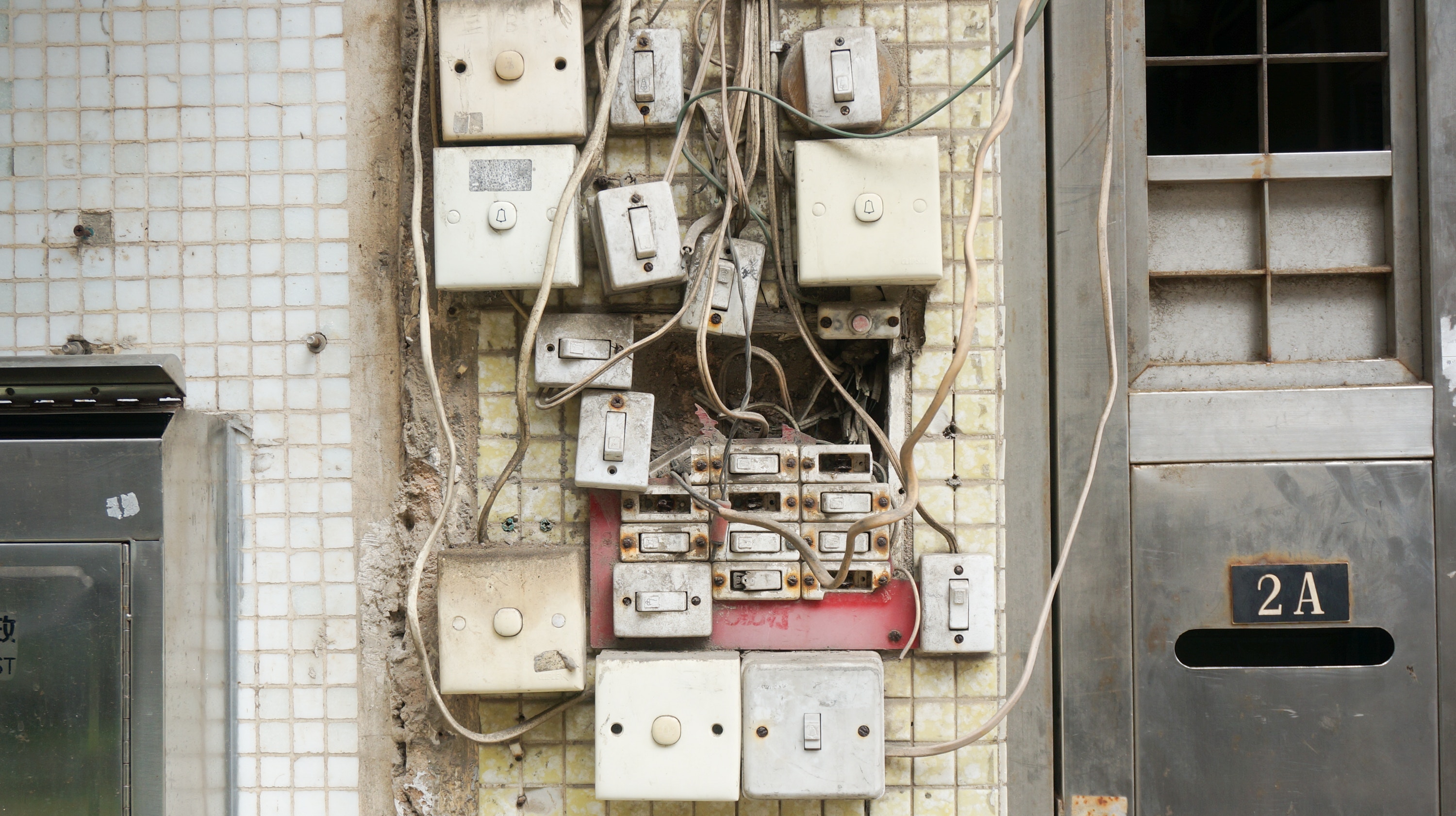Messy electrical switches and wires on a tiled wall in Macau HD Wallpaper