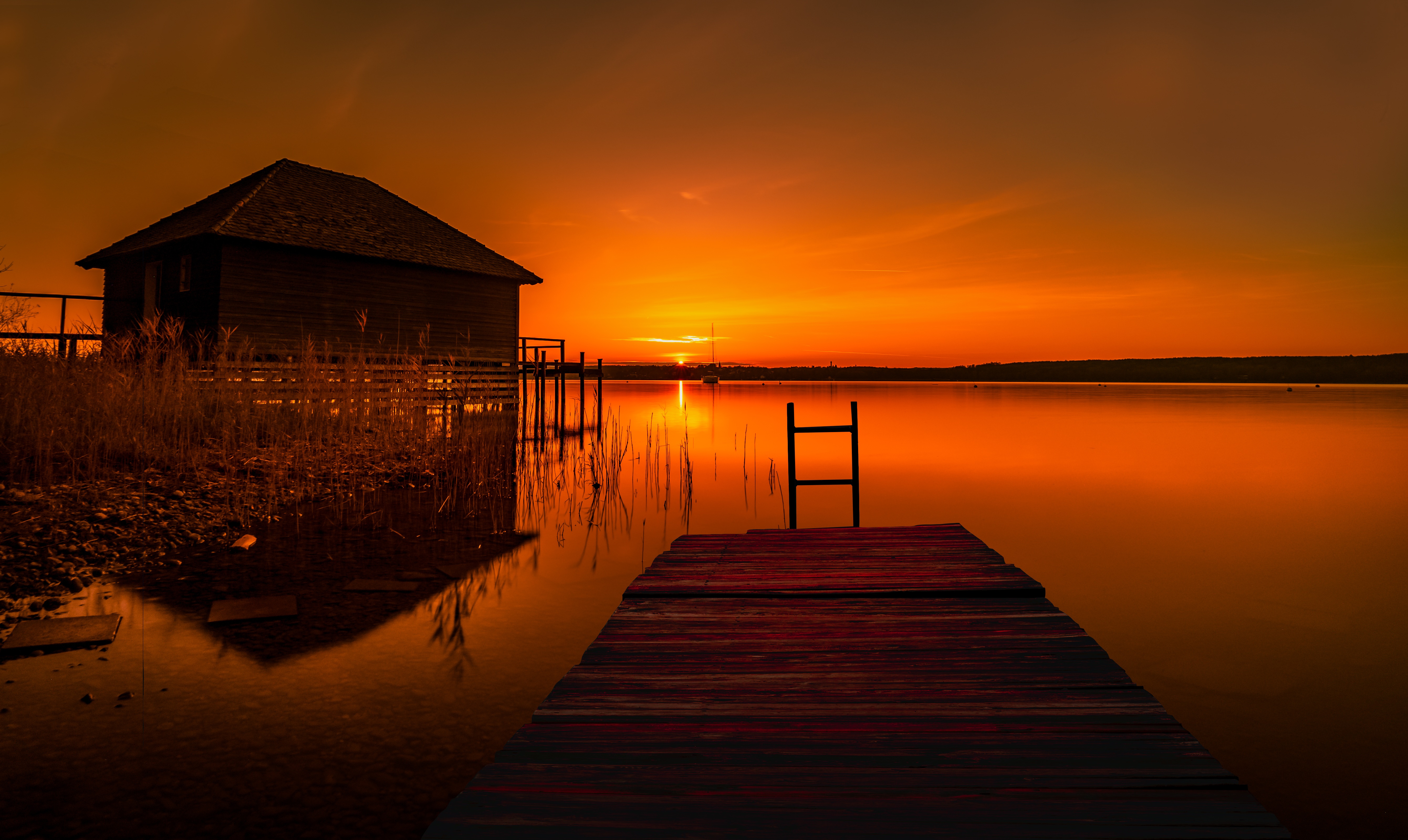 Wooden pier and boathouse at sunset over a lake HD Wallpaper