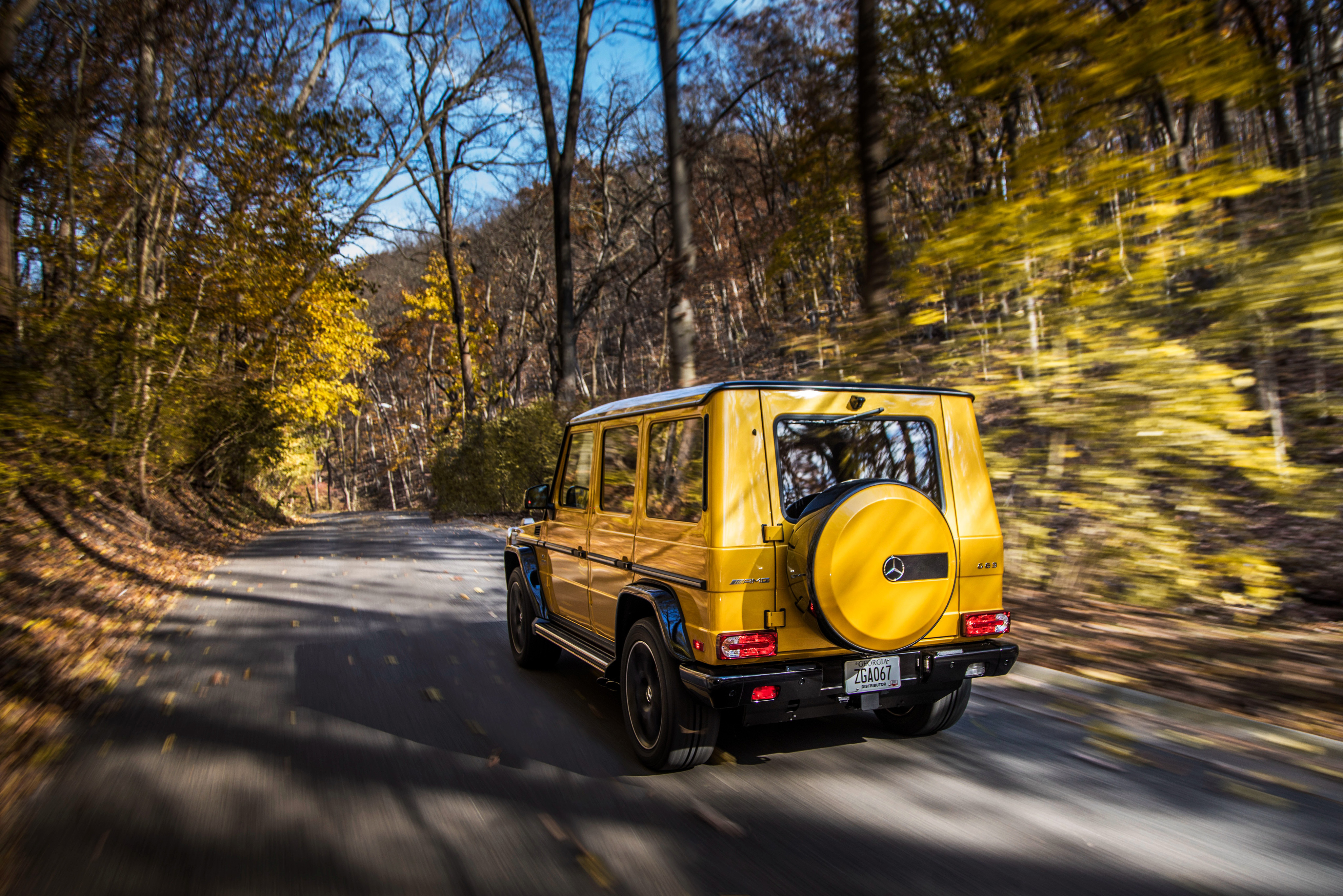Yellow Mercedes-AMG G-Class driving on a road in autumn HD Wallpaper