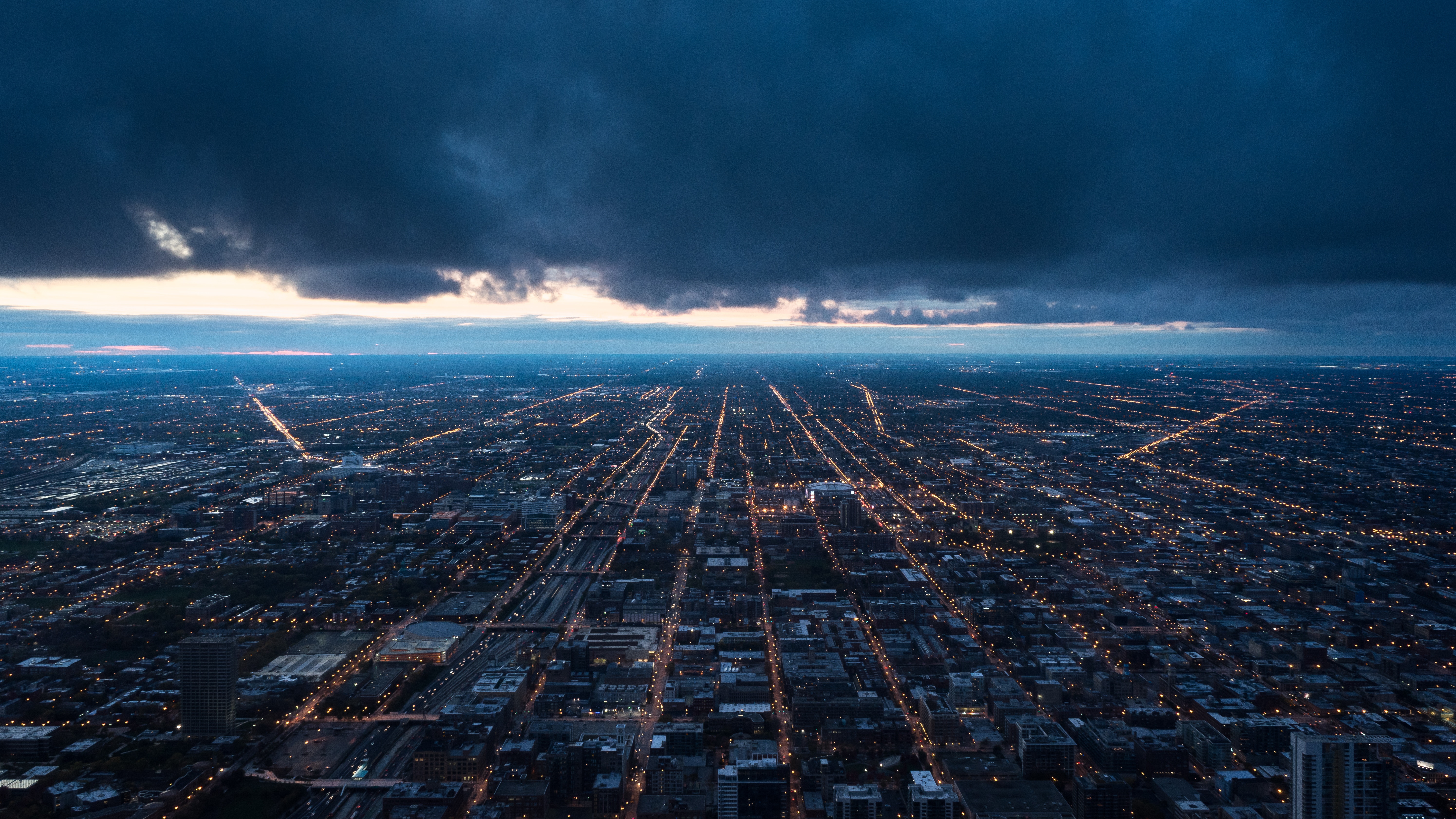 Aerial view of city lights at dusk with stormy clouds HD Wallpaper