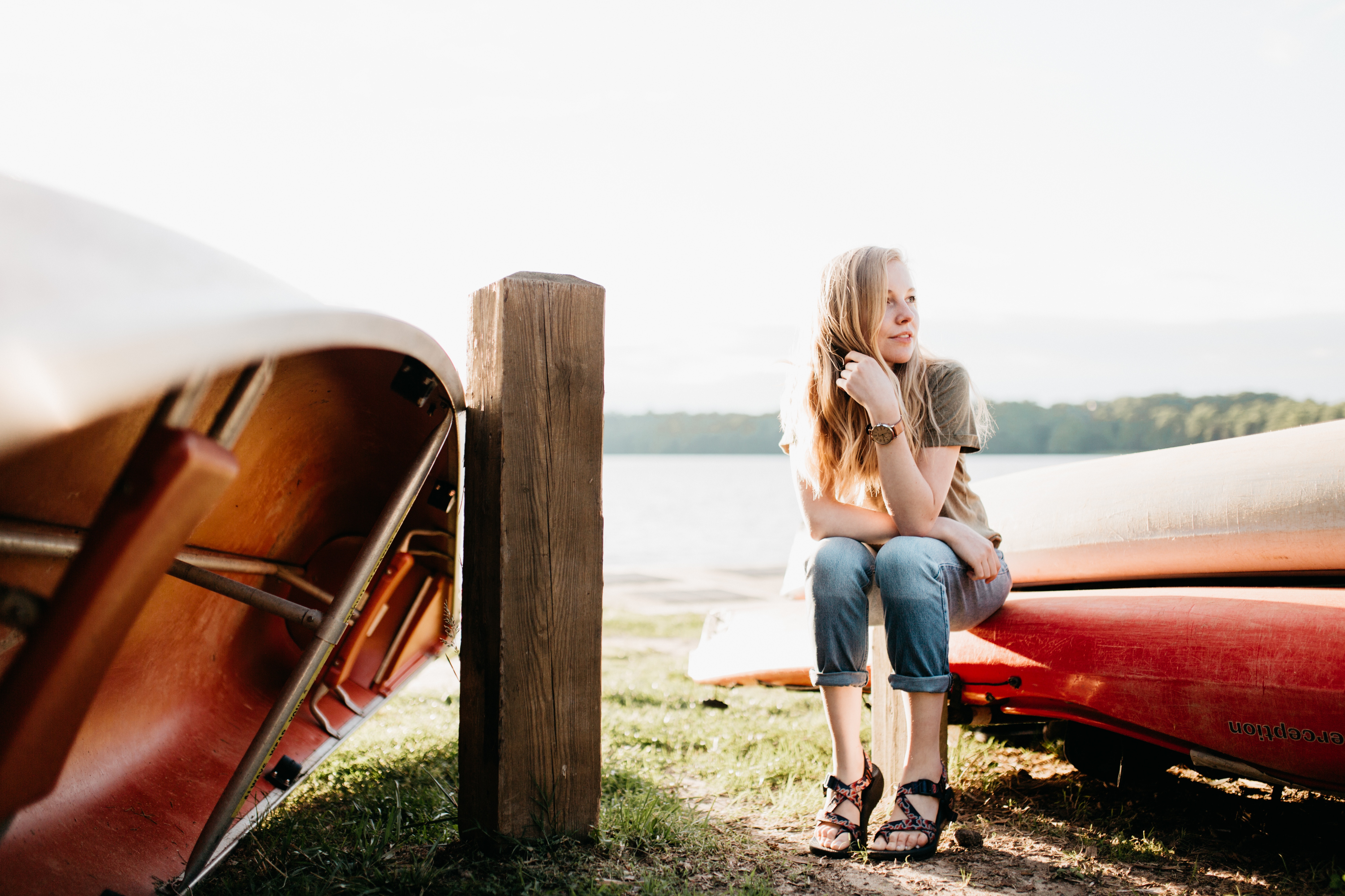 Woman sitting on canoes by a lake HD Wallpaper