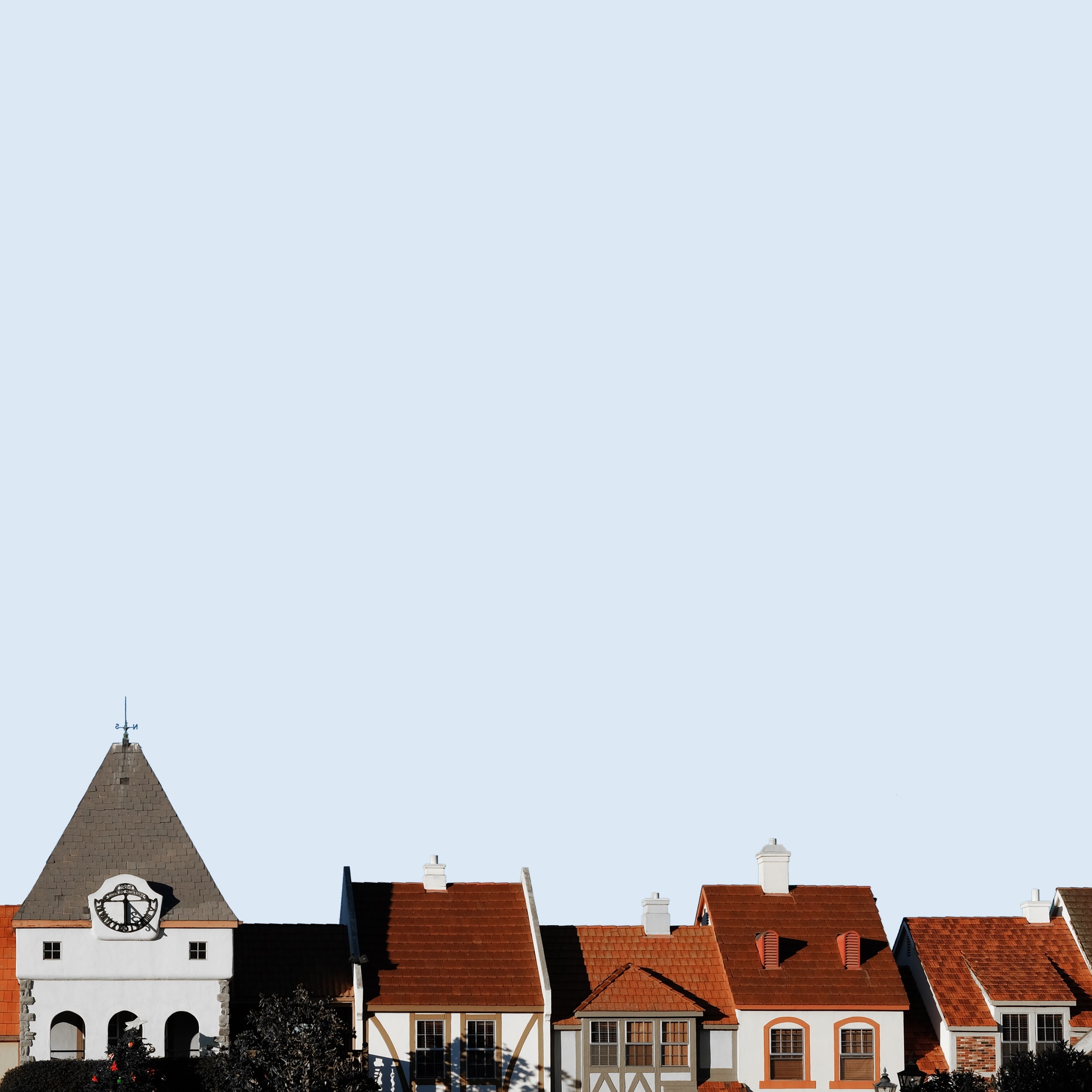 Row of European-style houses with red roofs under a clear sky HD Wallpaper