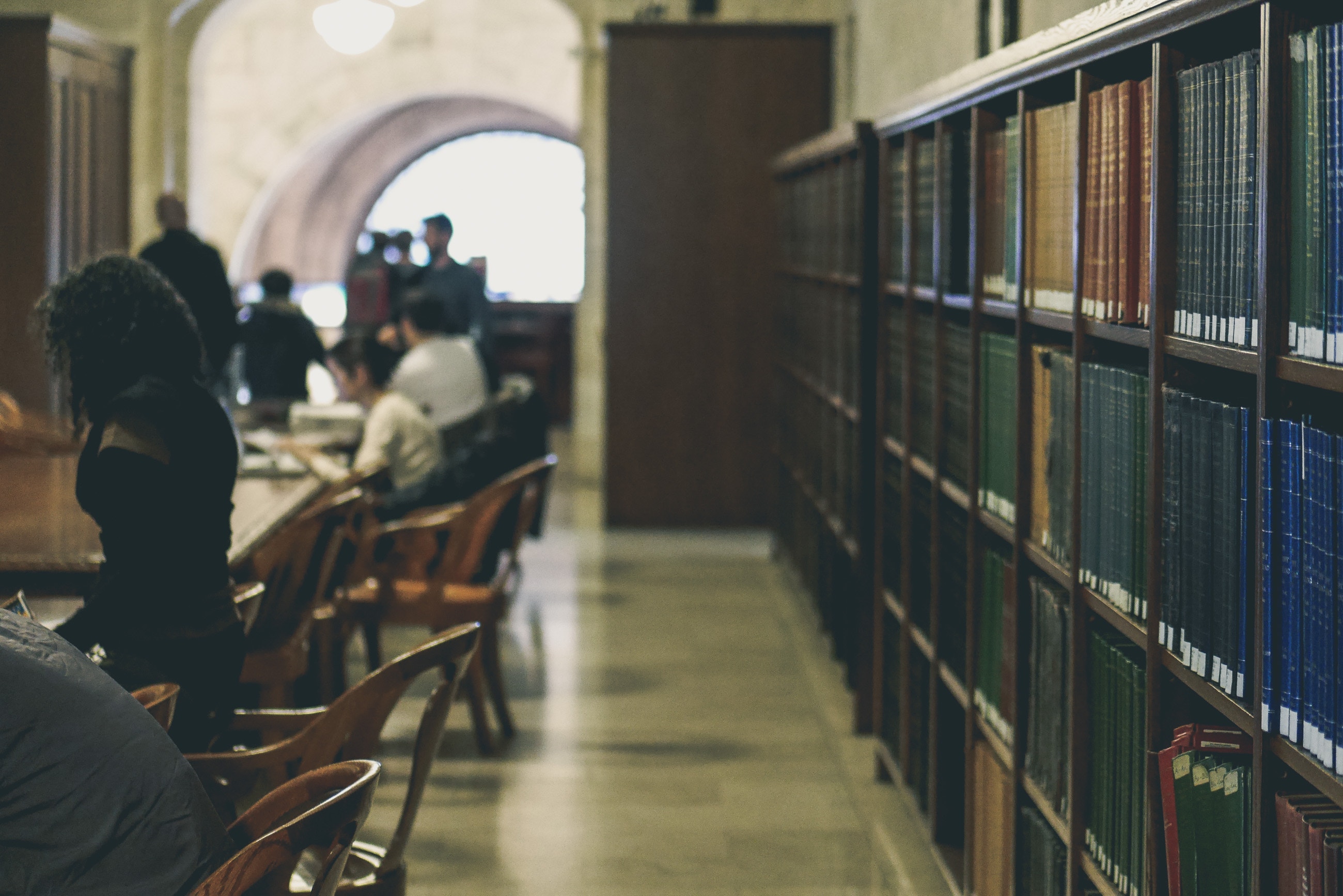 People studying in a vintage library with bookshelves HD Wallpaper