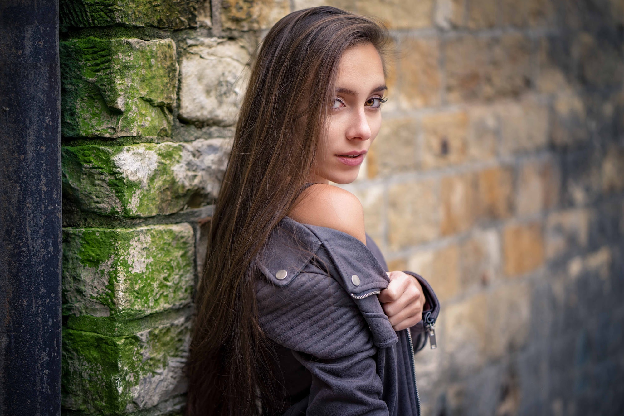 Young woman posing against a brick wall HD Wallpaper