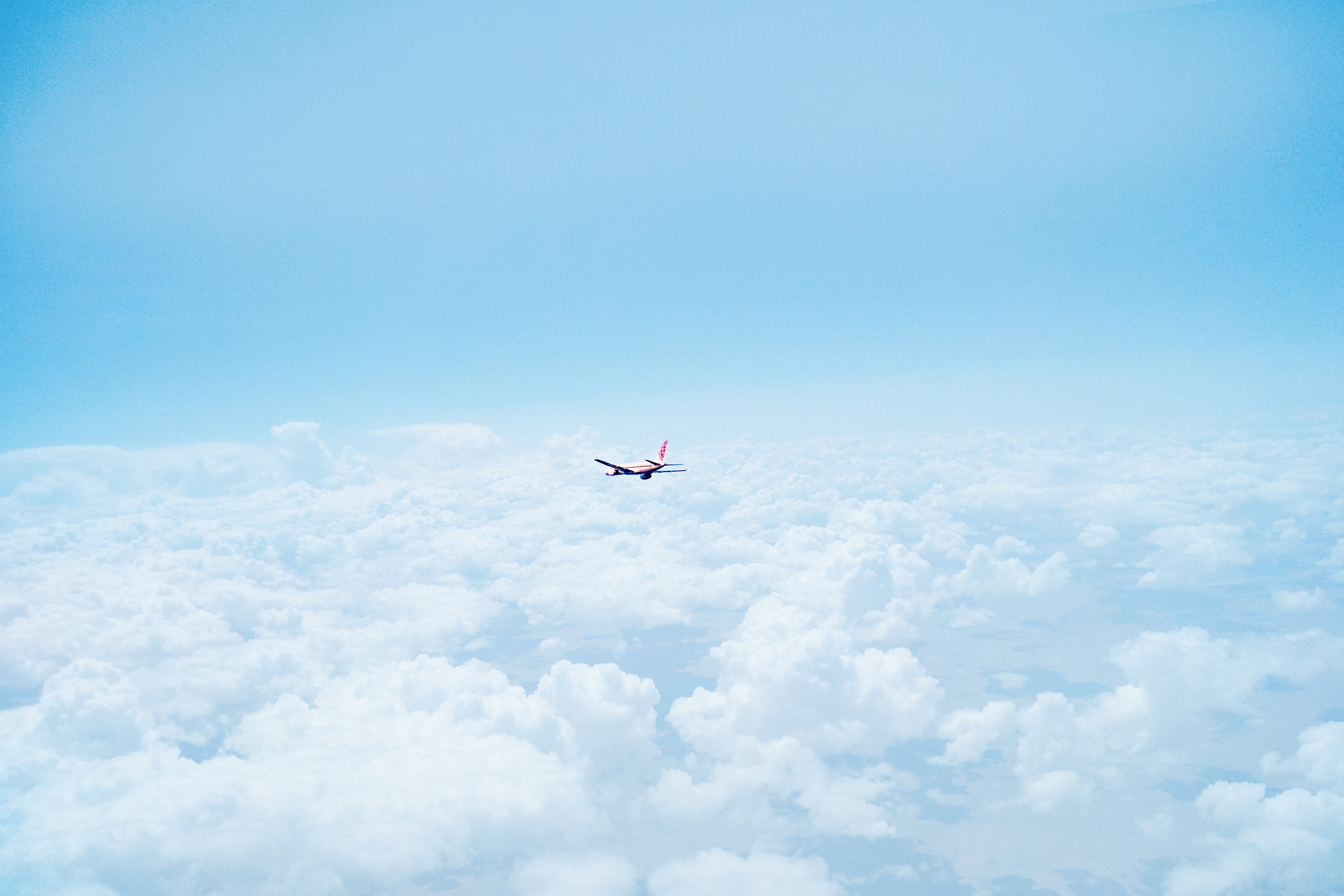 Airplane flying over clouds in a blue sky HD Wallpaper
