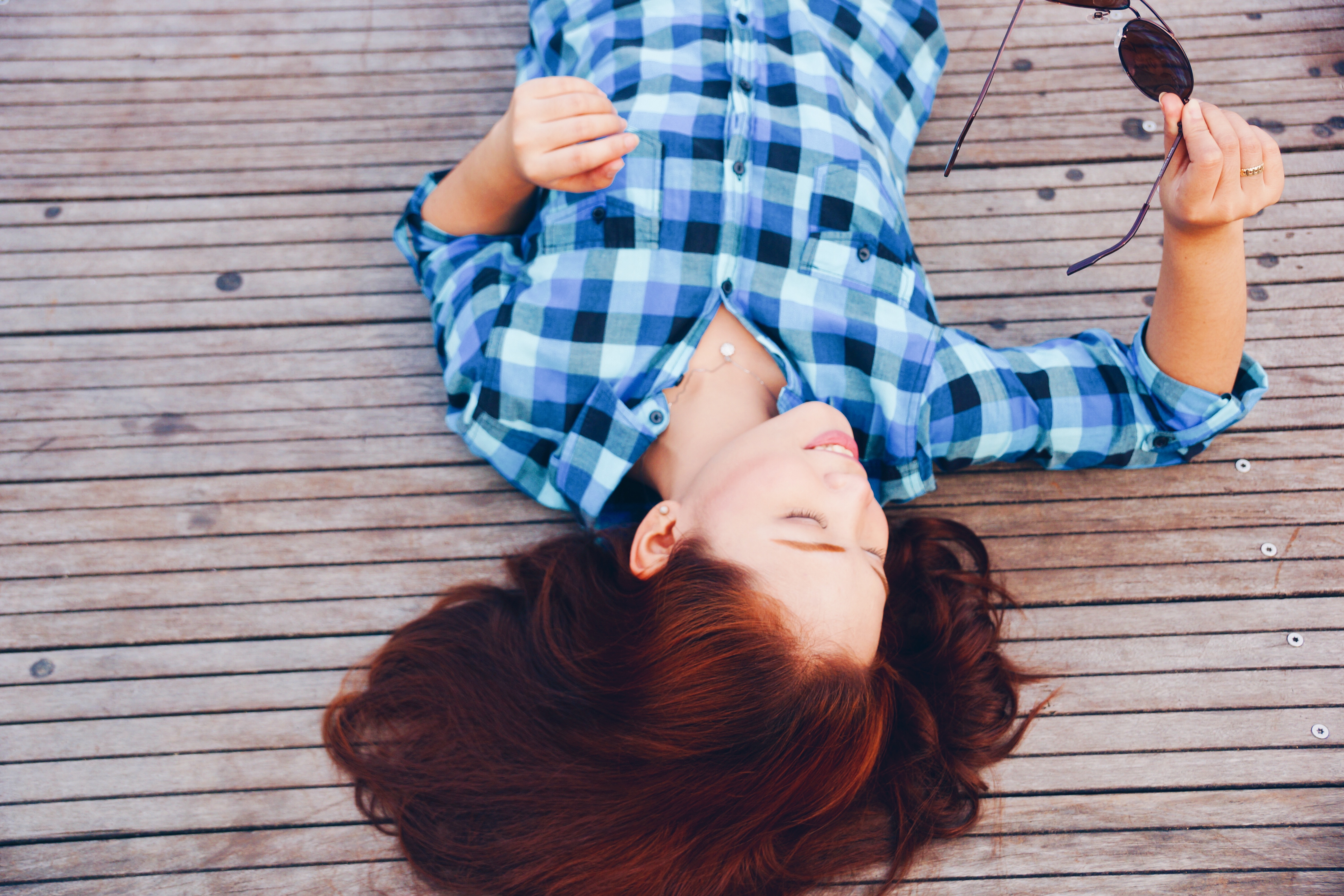 Woman in Plaid Shirt Lying on Wooden Deck Holding Sunglasses HD Wallpaper