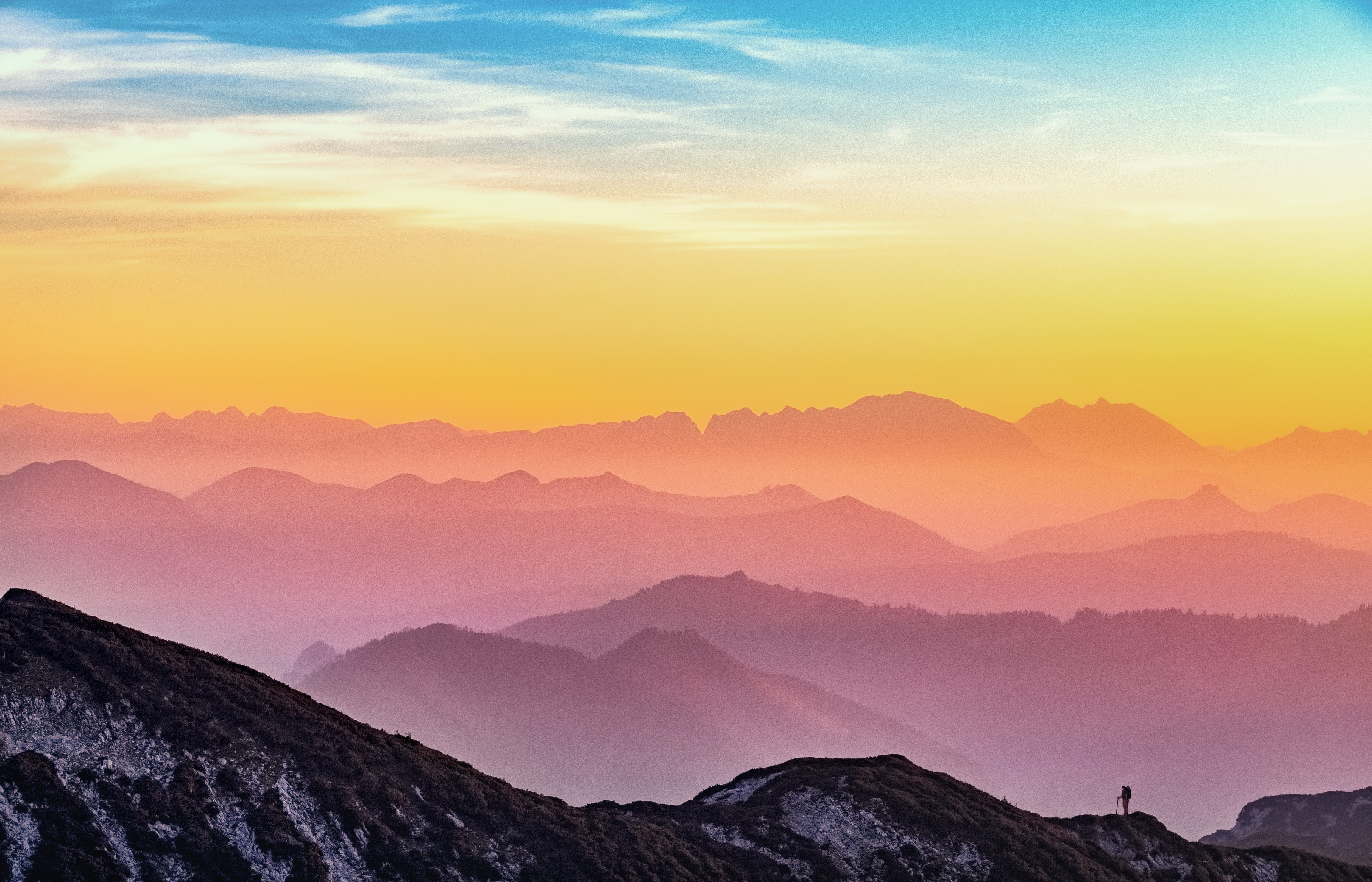 Mountain range at sunset with a lone hiker HD Wallpaper
