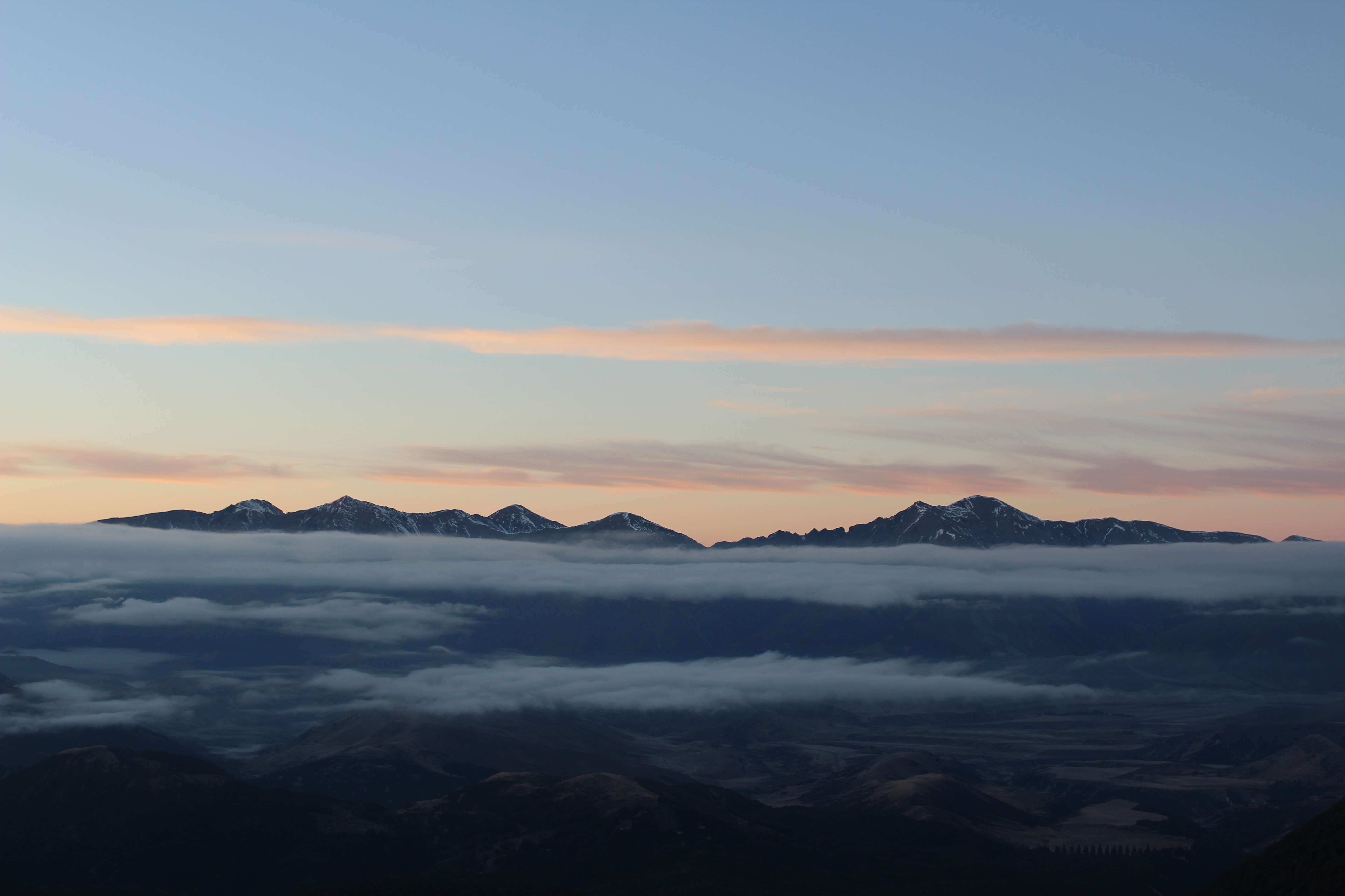 Mountains shrouded in fog at sunrise with pink clouds HD Wallpaper