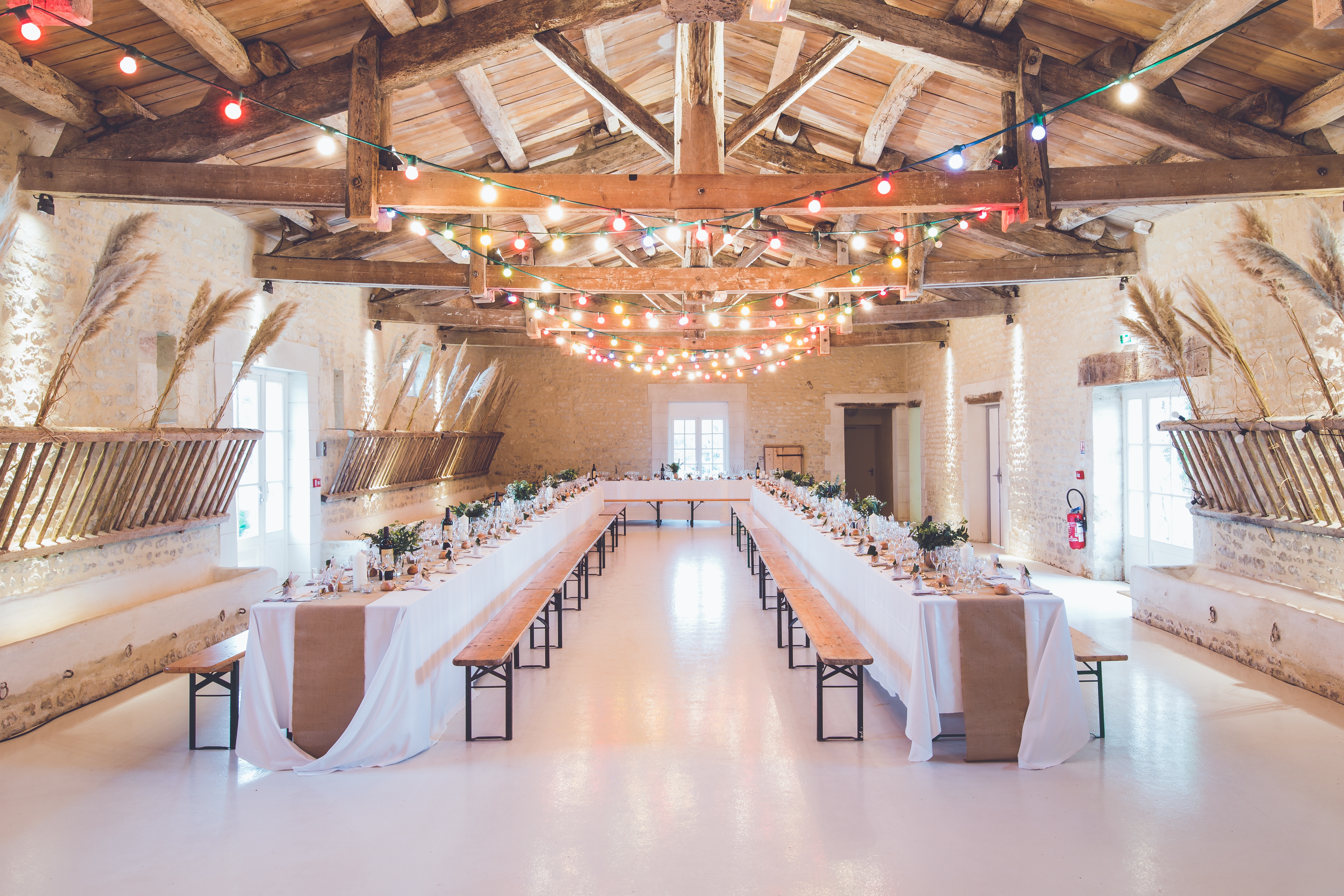 Indoor wedding reception hall with banquet tables and string lights HD Wallpaper