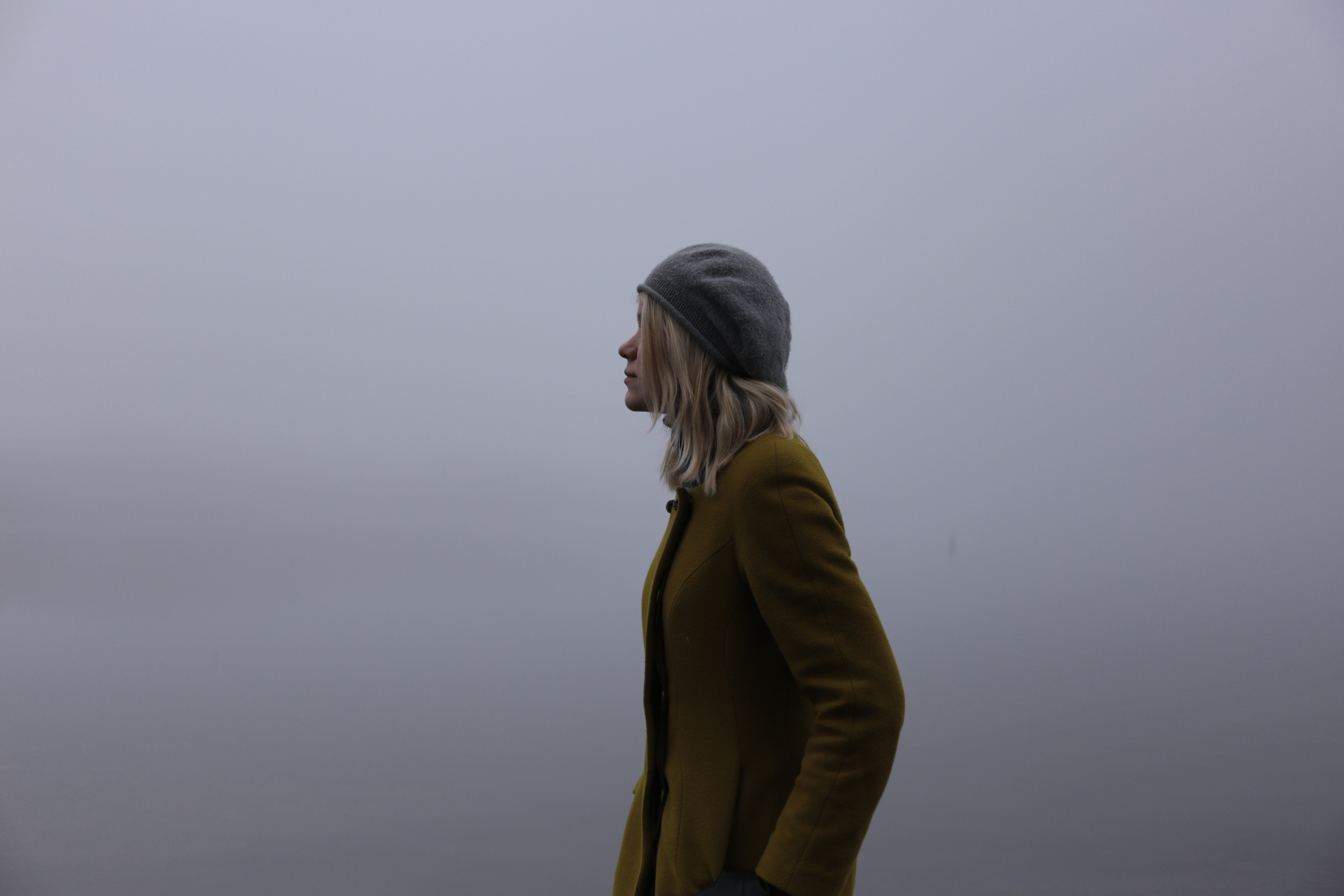 Woman in yellow coat and hat in fog HD Wallpaper