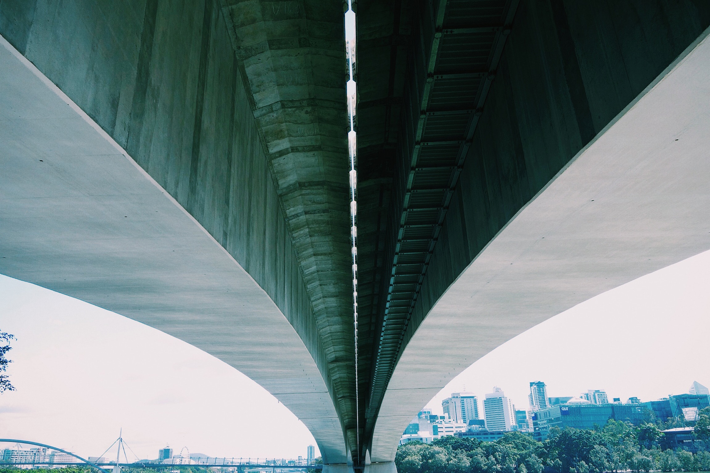 Underneath a concrete bridge with a cityscape in the background HD Wallpaper