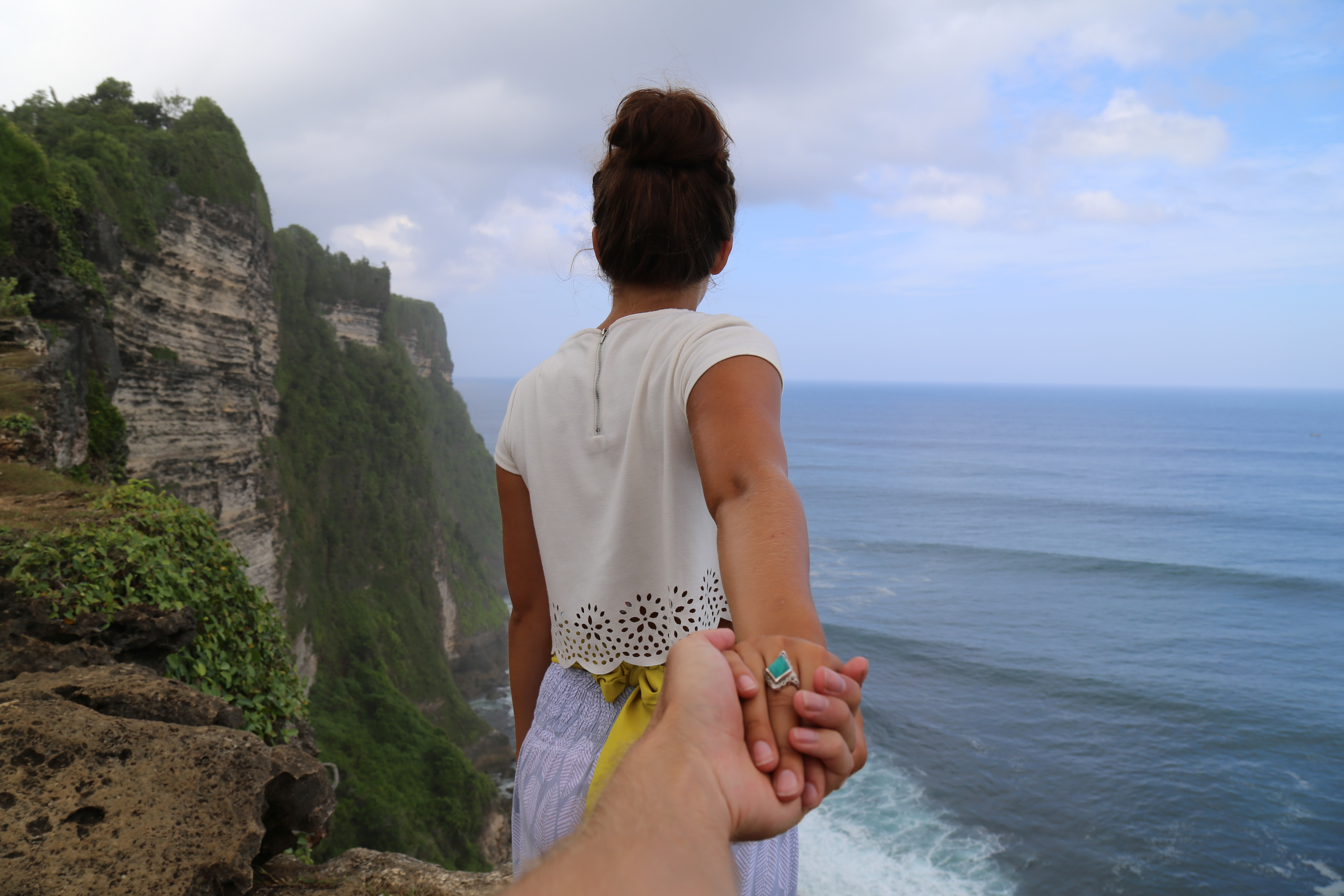 Woman holding hand on cliff overlooking ocean HD Wallpaper