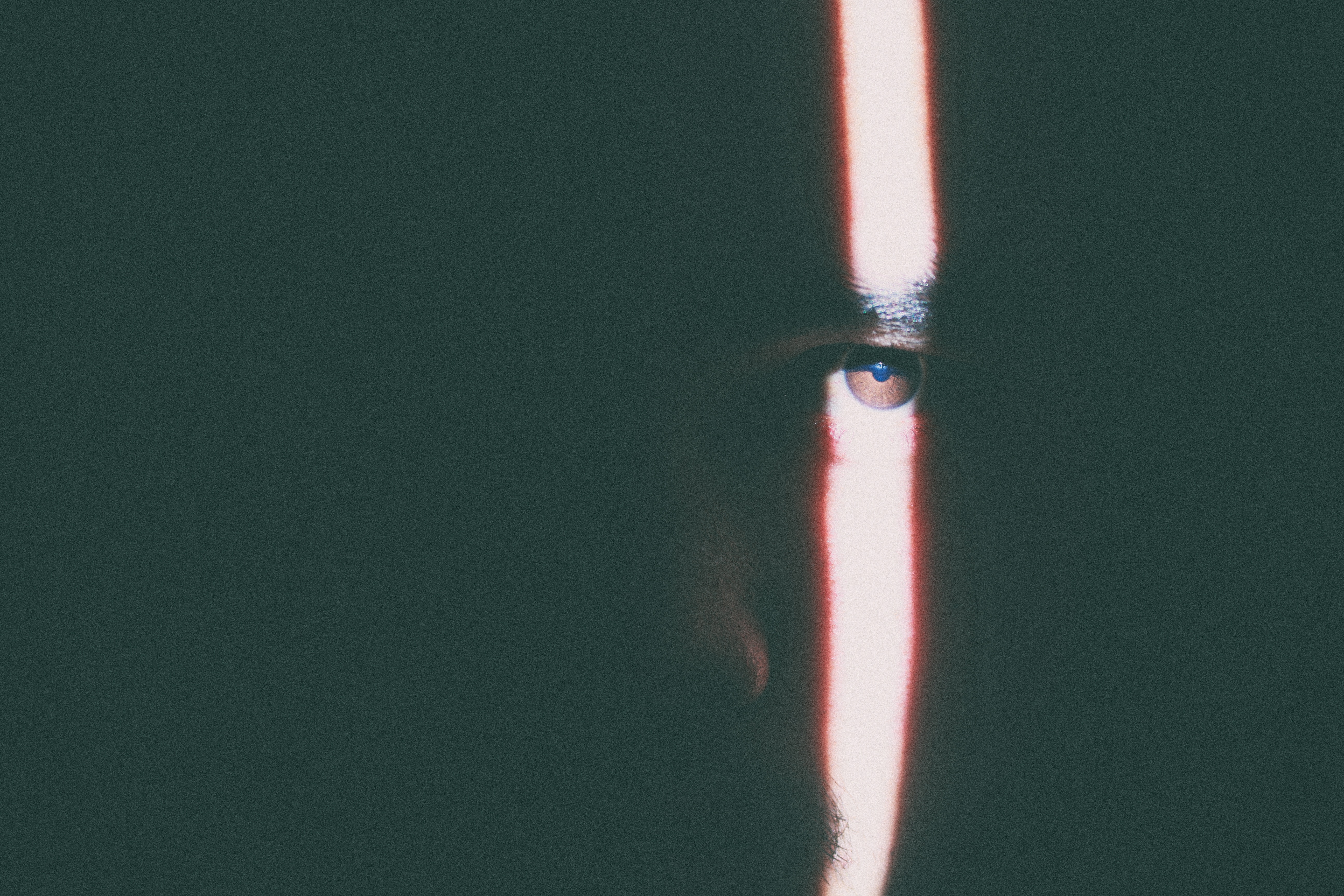 Man's eye illuminated by a vertical light beam HD Wallpaper