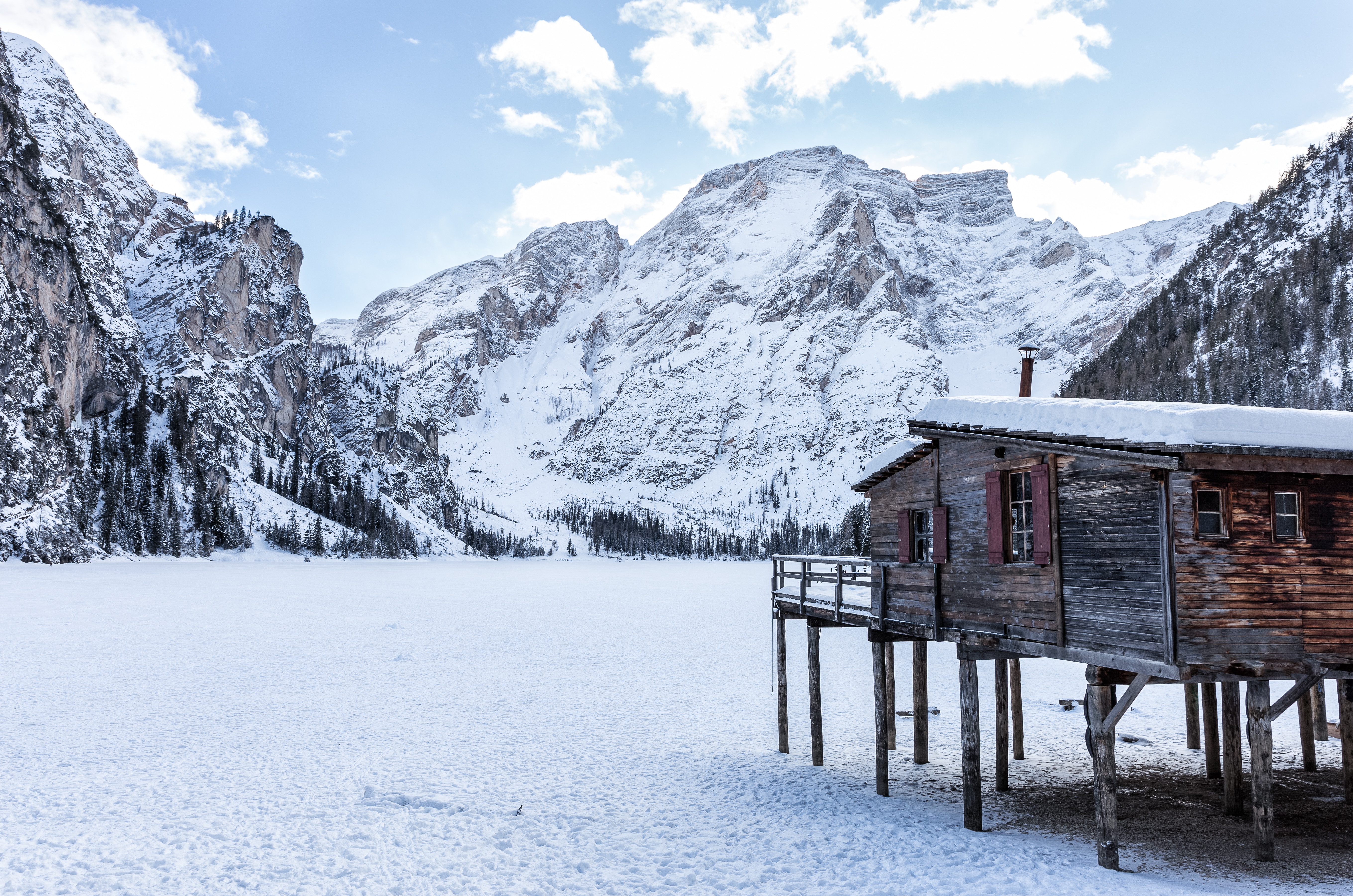 Wooden cabin on stilts in a snowy mountain landscape HD Wallpaper