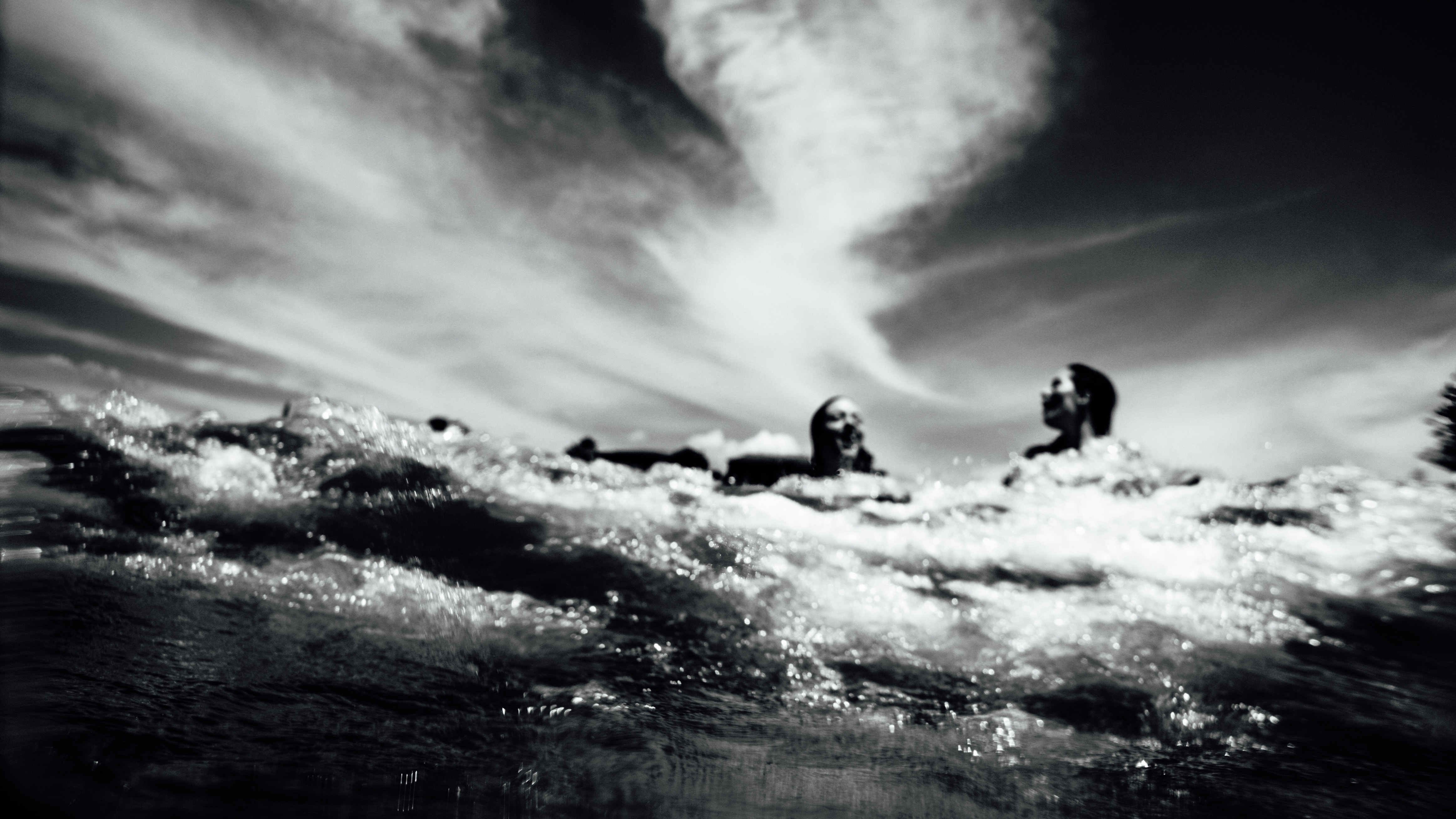 People swimming in the ocean under a cloudy sky HD Wallpaper
