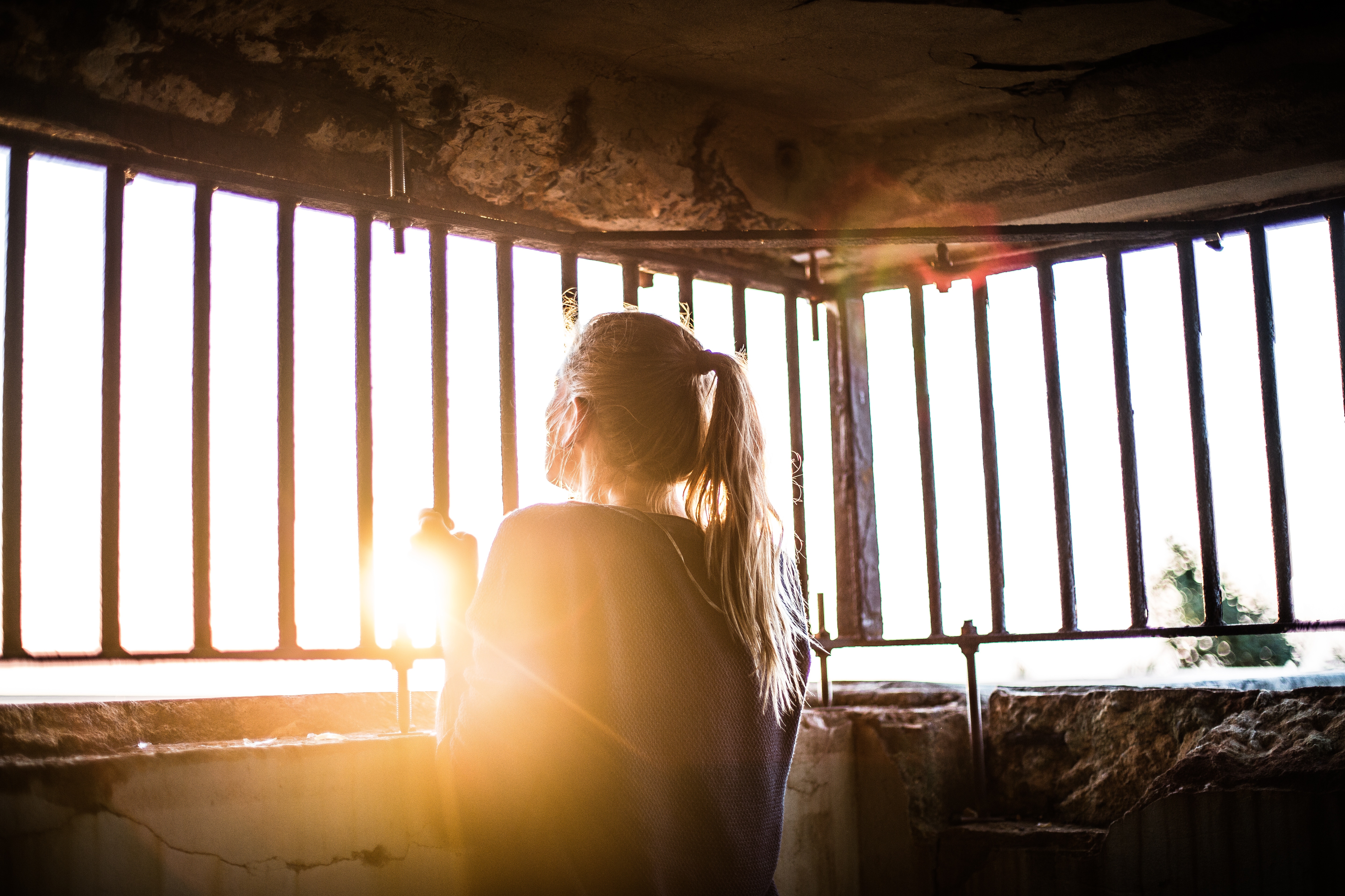 Girl looking out through bars at sunrise HD Wallpaper