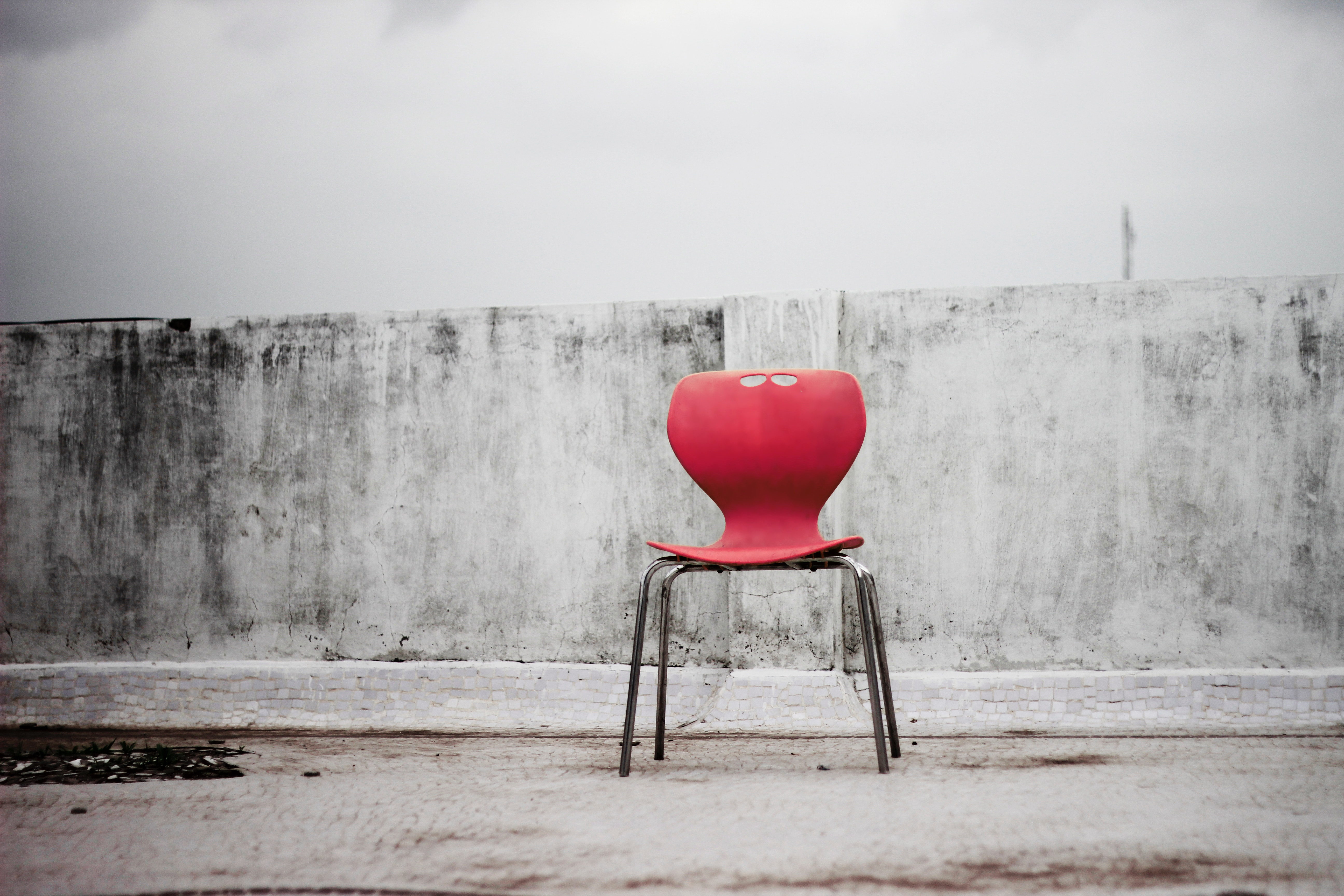 A red chair against a textured wall HD Wallpaper