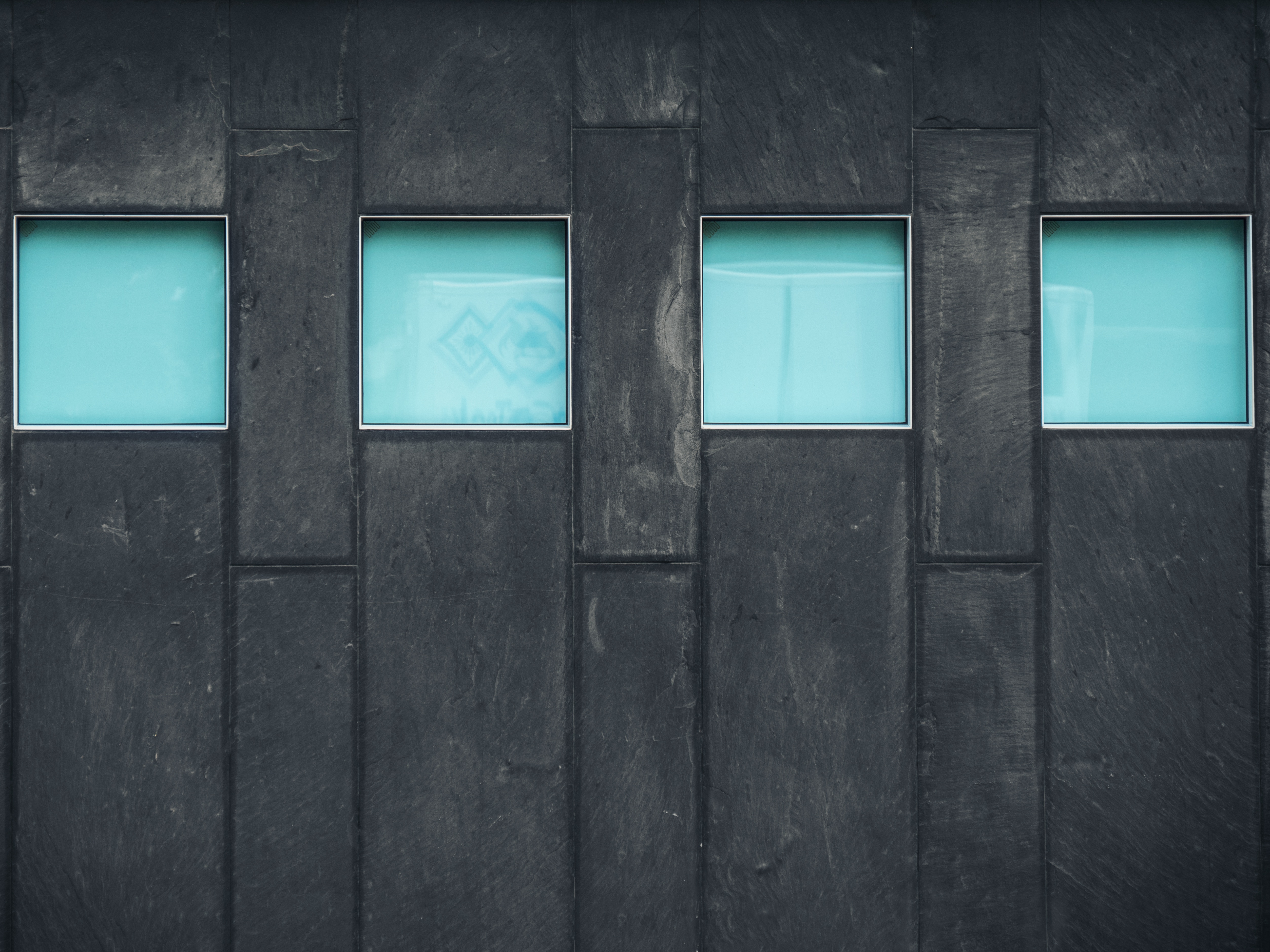 Four blue windows on a dark stone facade HD Wallpaper