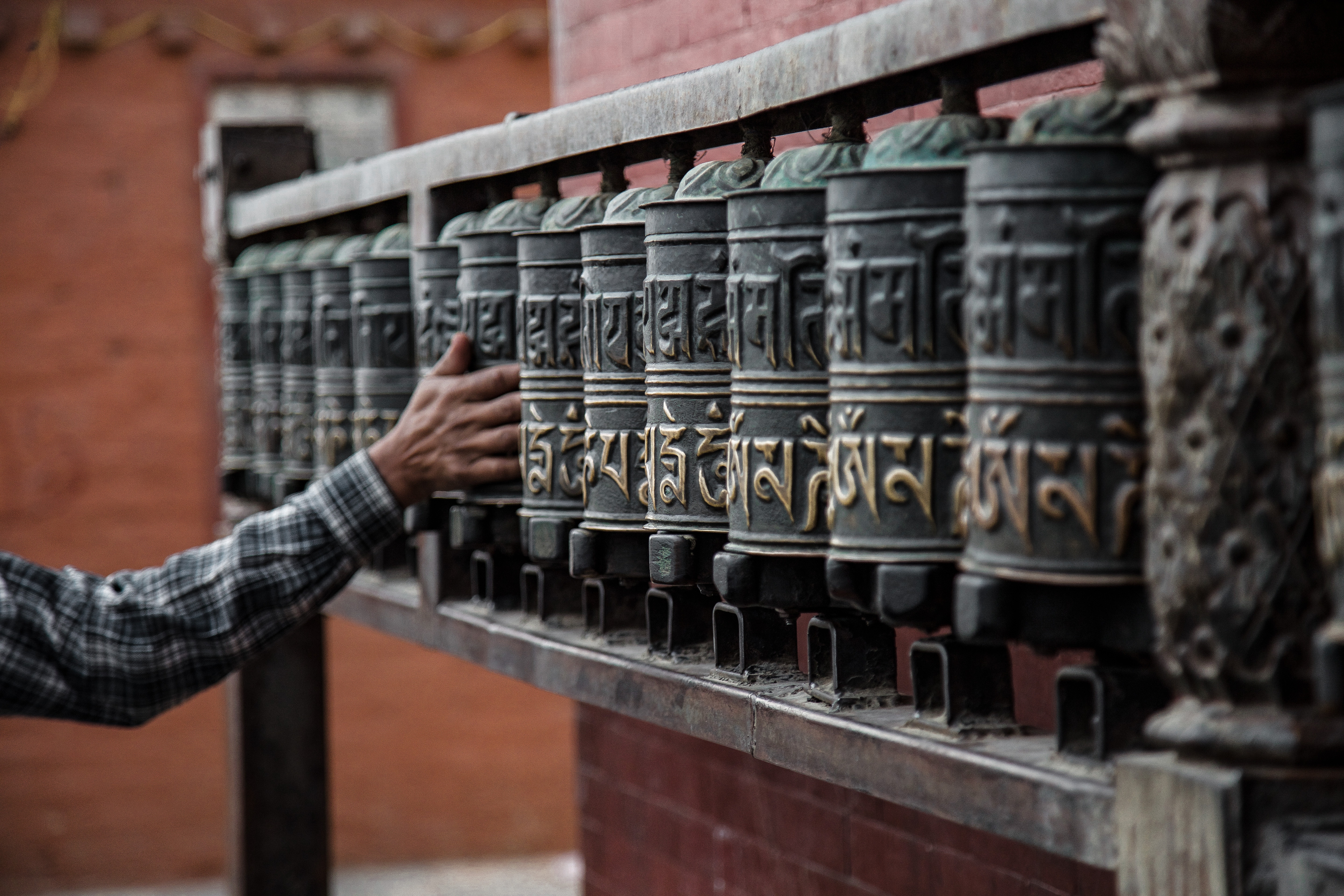 Man spinning prayer wheels in a temple HD Wallpaper