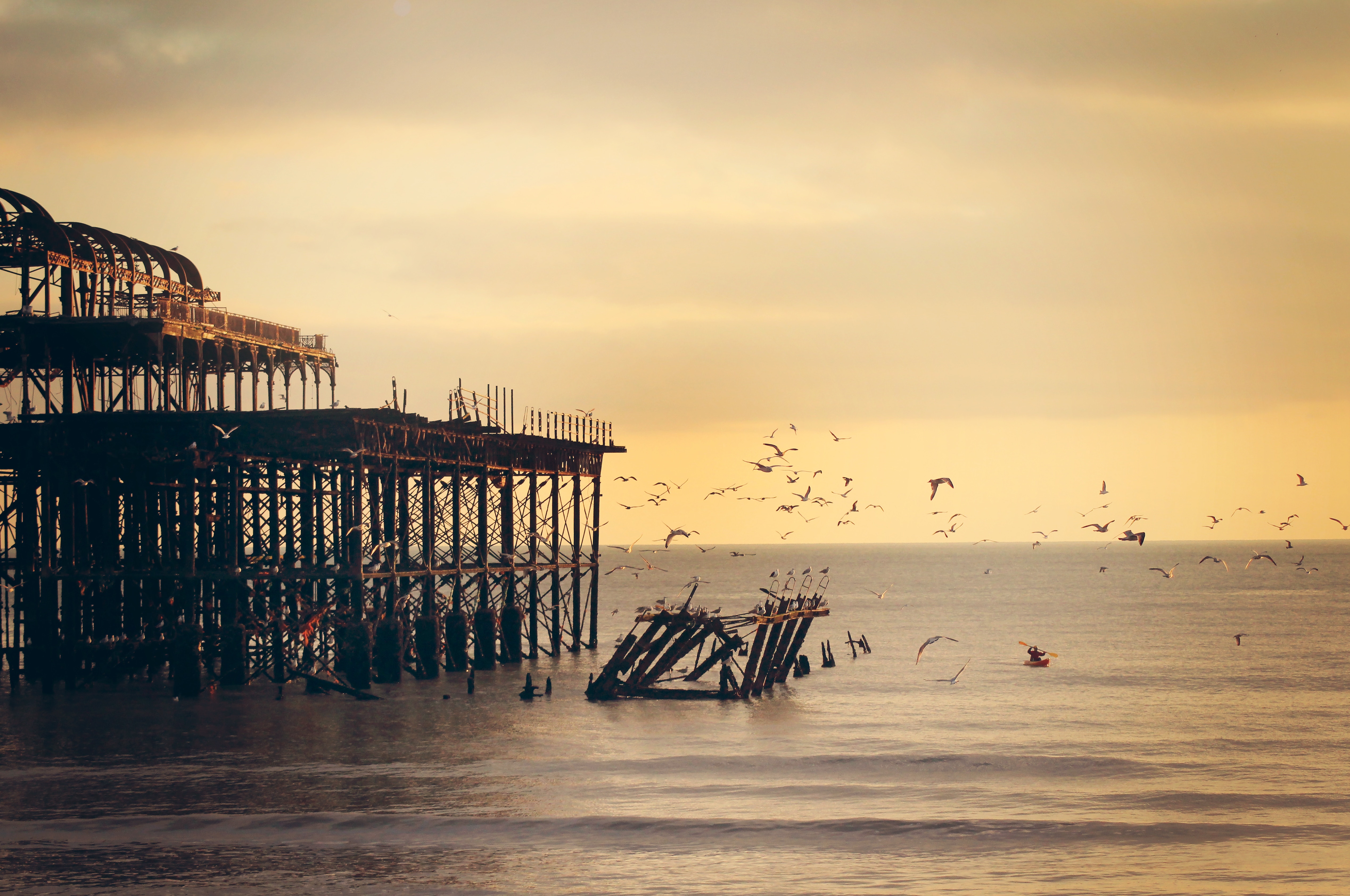 West Pier Brighton at sunset with seagulls and kayaker HD Wallpaper