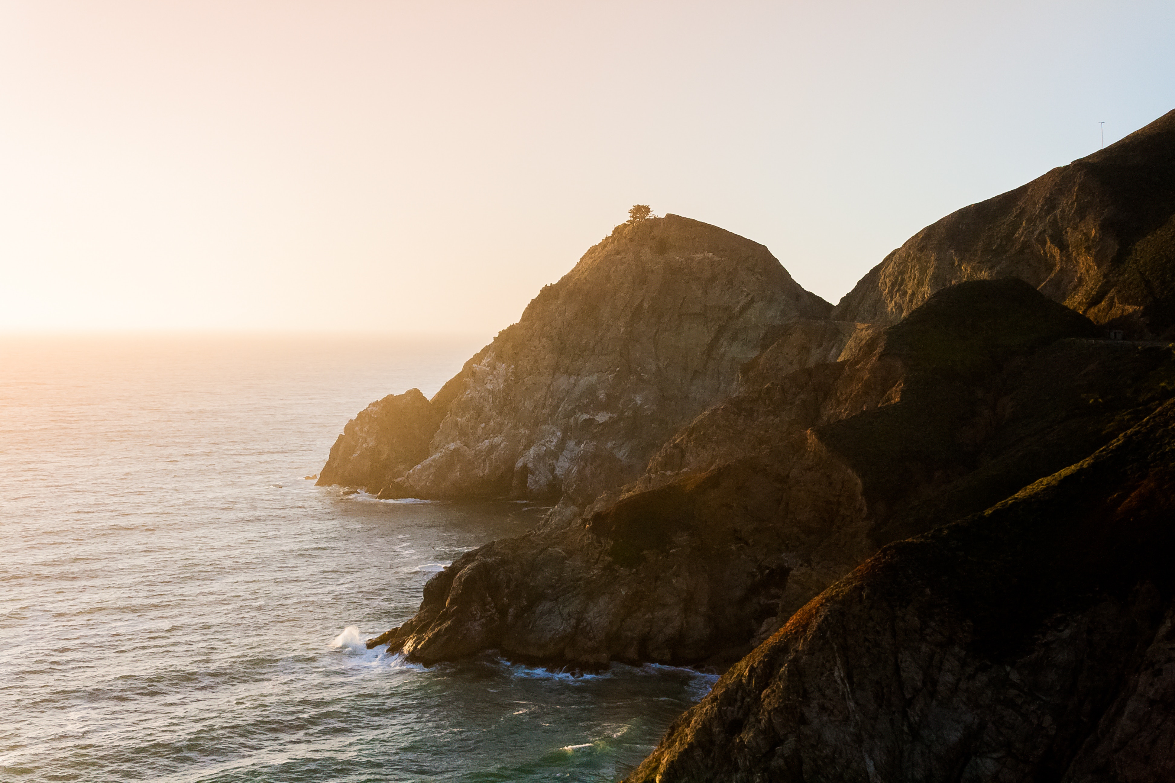 Rocky coastline with ocean waves at sunset HD Wallpaper