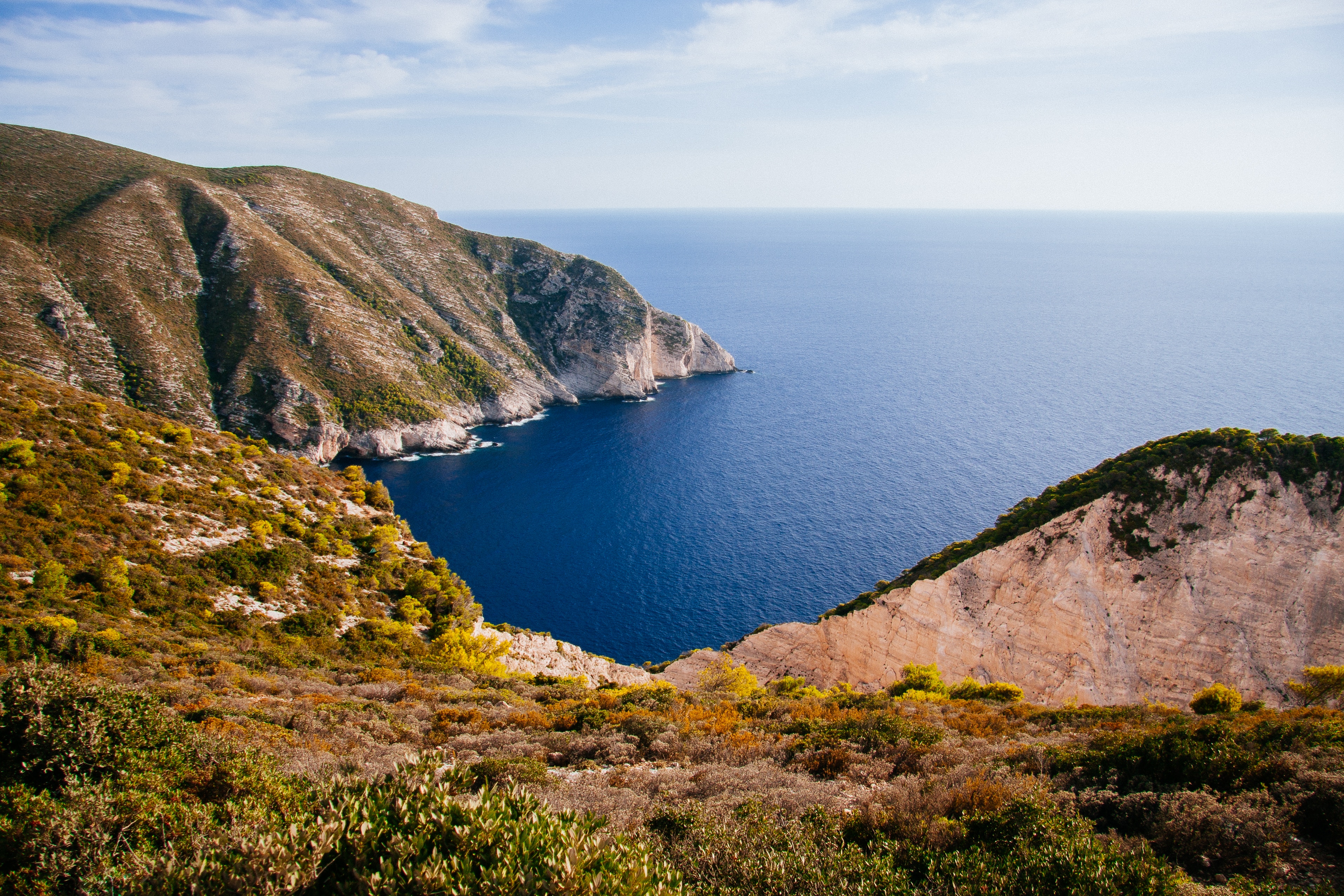 Coastal cliffs overlooking a deep blue bay HD Wallpaper