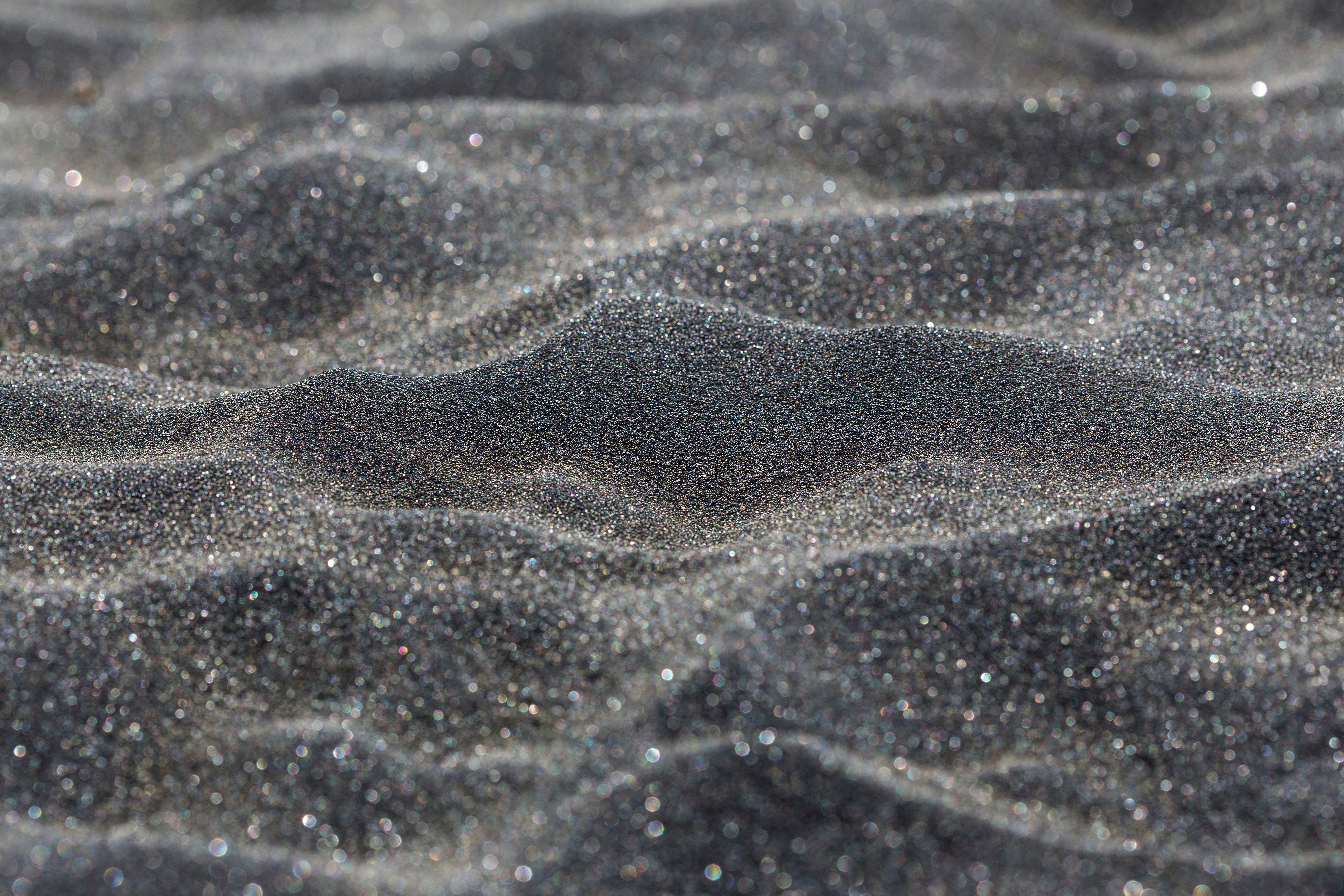 Close-up of black sand dunes with sparkling particles HD Wallpaper