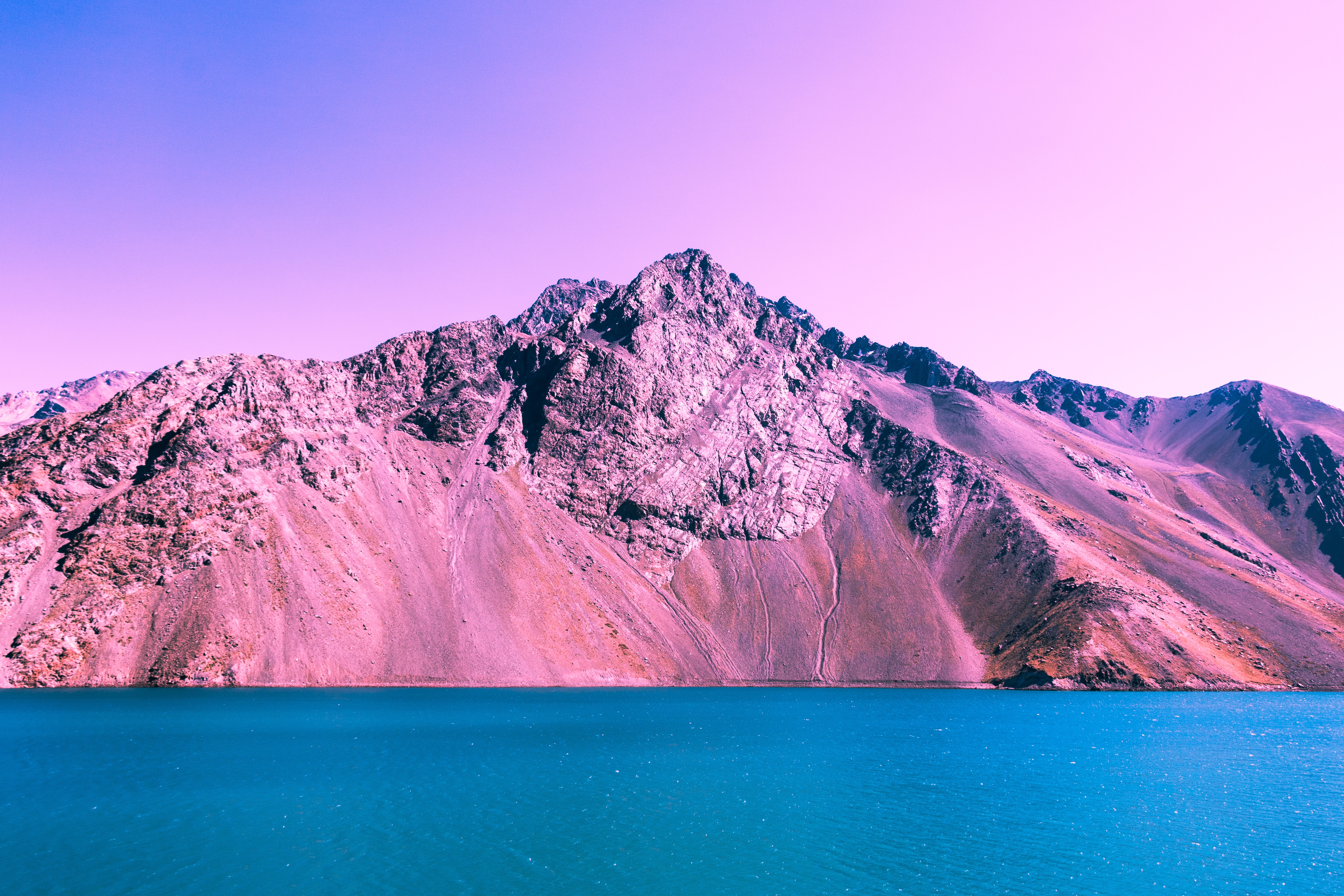 Purple and pink mountains overlooking a blue lake HD Wallpaper