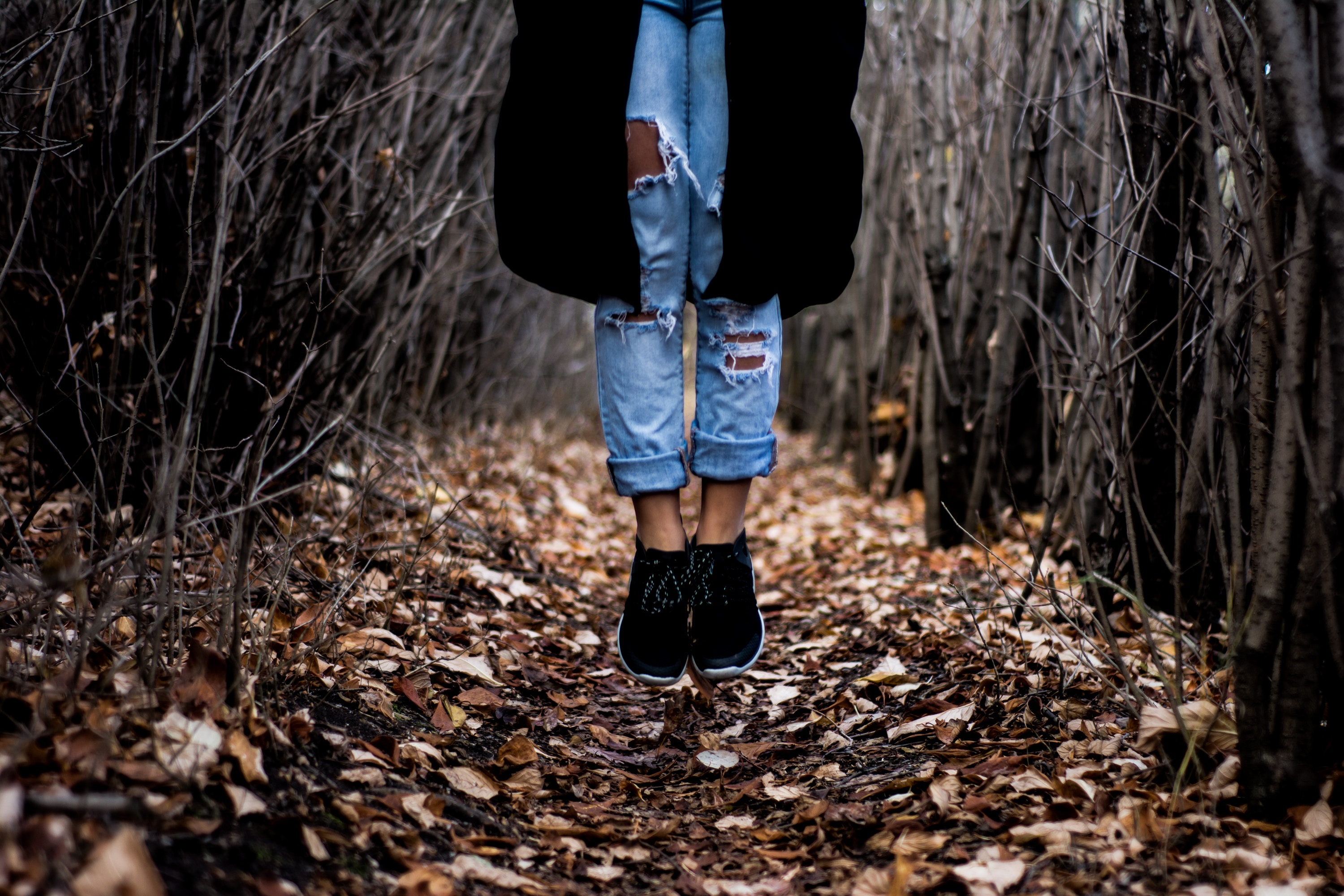 Person jumping in a forest with ripped jeans HD Wallpaper