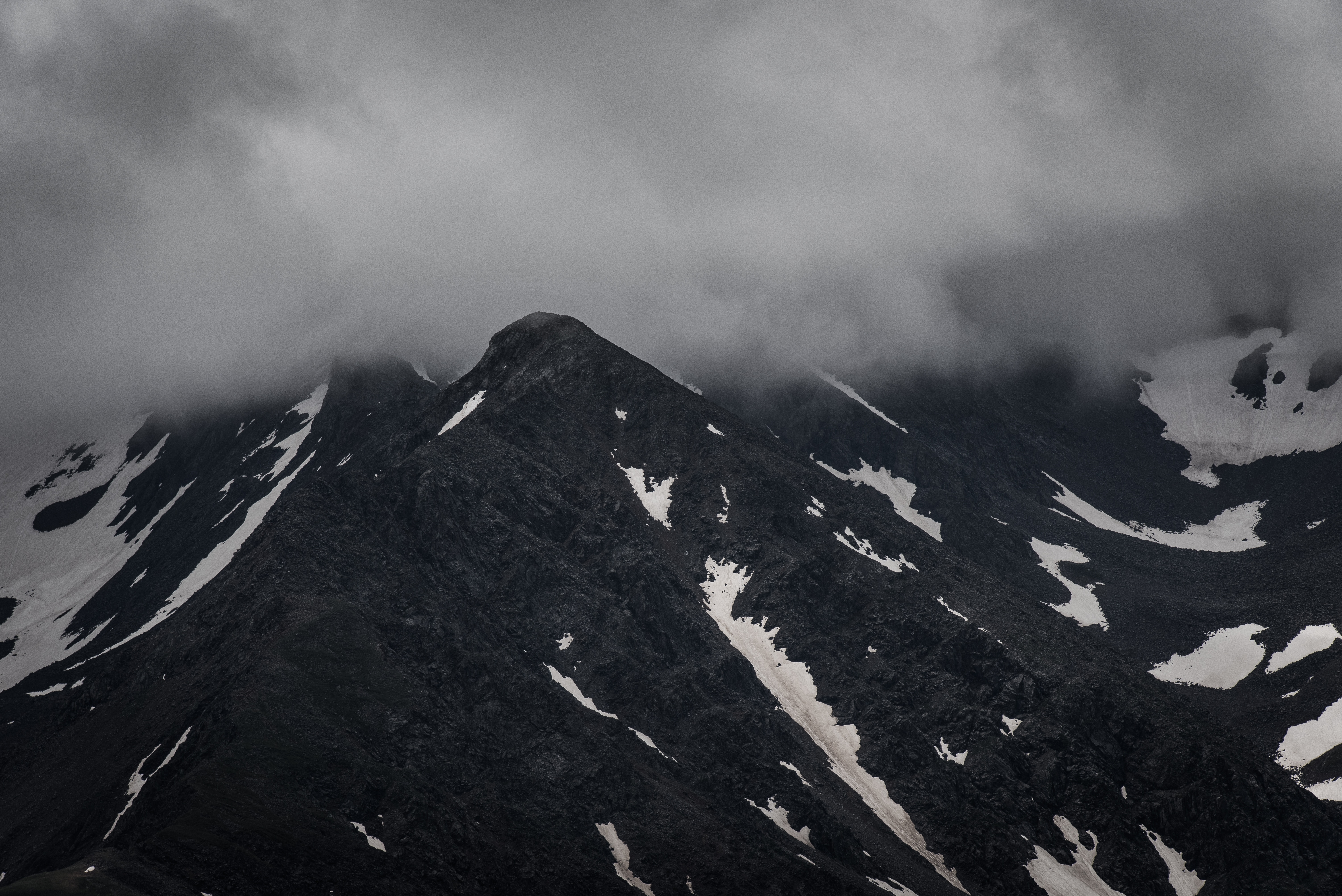 Dark mountain peak with snow under overcast sky HD Wallpaper