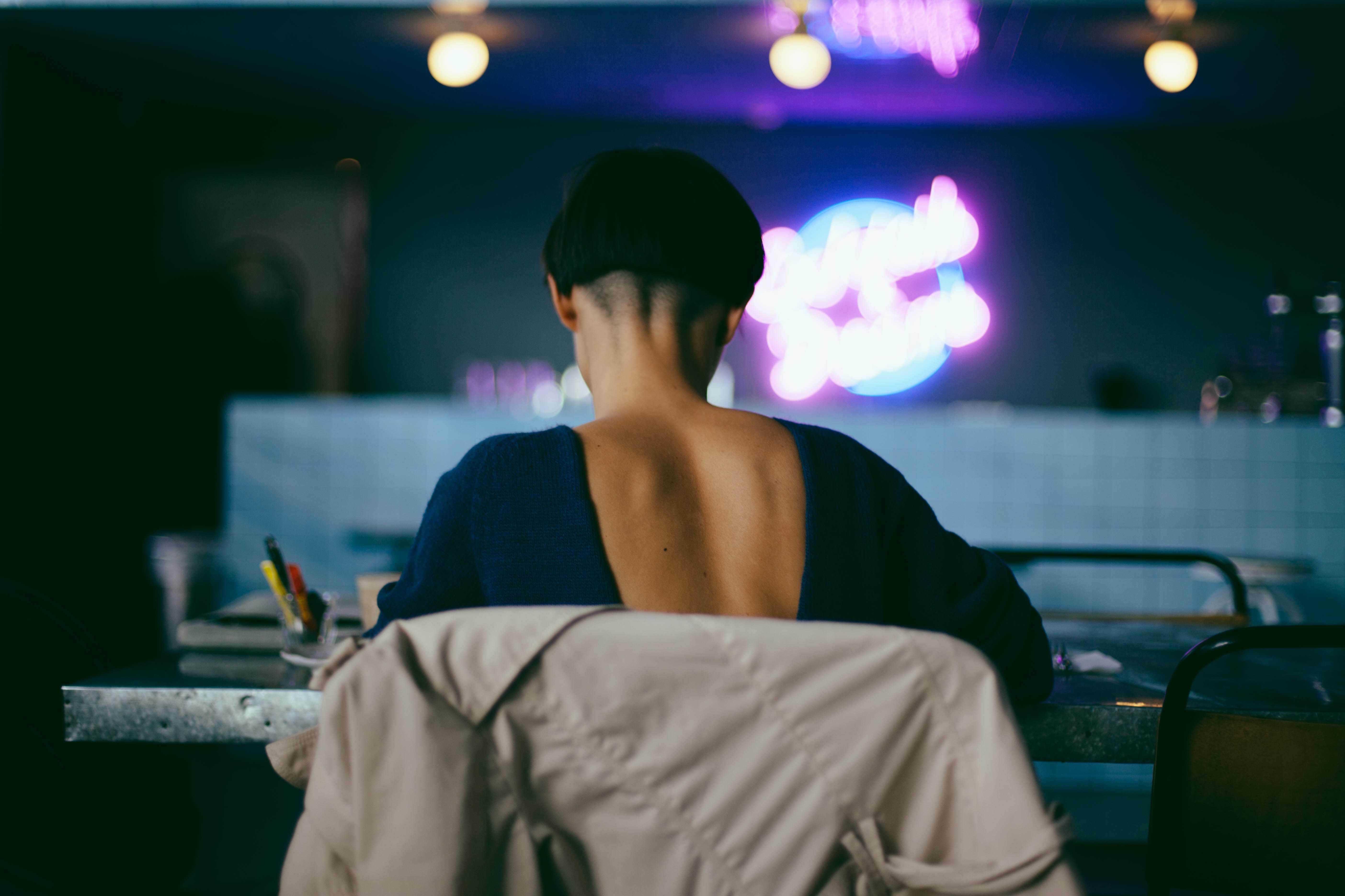 Woman with short hair at a table with neon lights HD Wallpaper