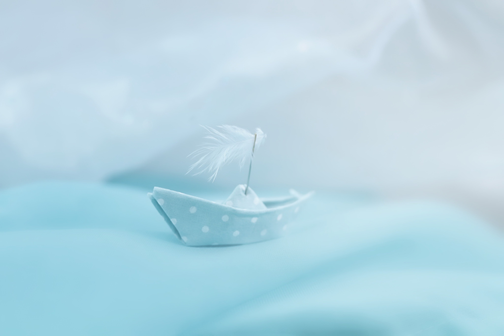 Origami paper boat with feather sail on blue fabric HD Wallpaper