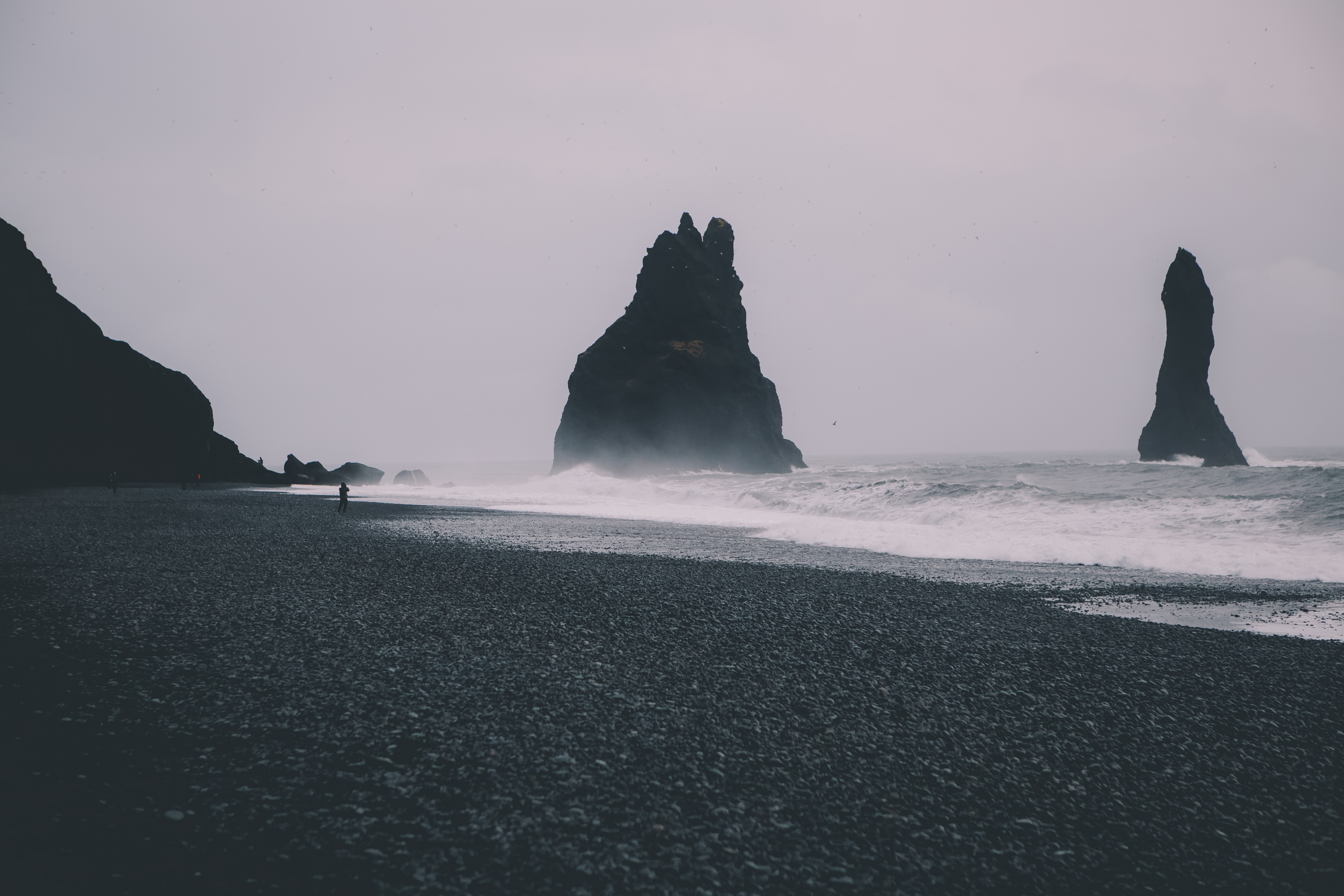 Black sand beach with rock formations and waves HD Wallpaper
