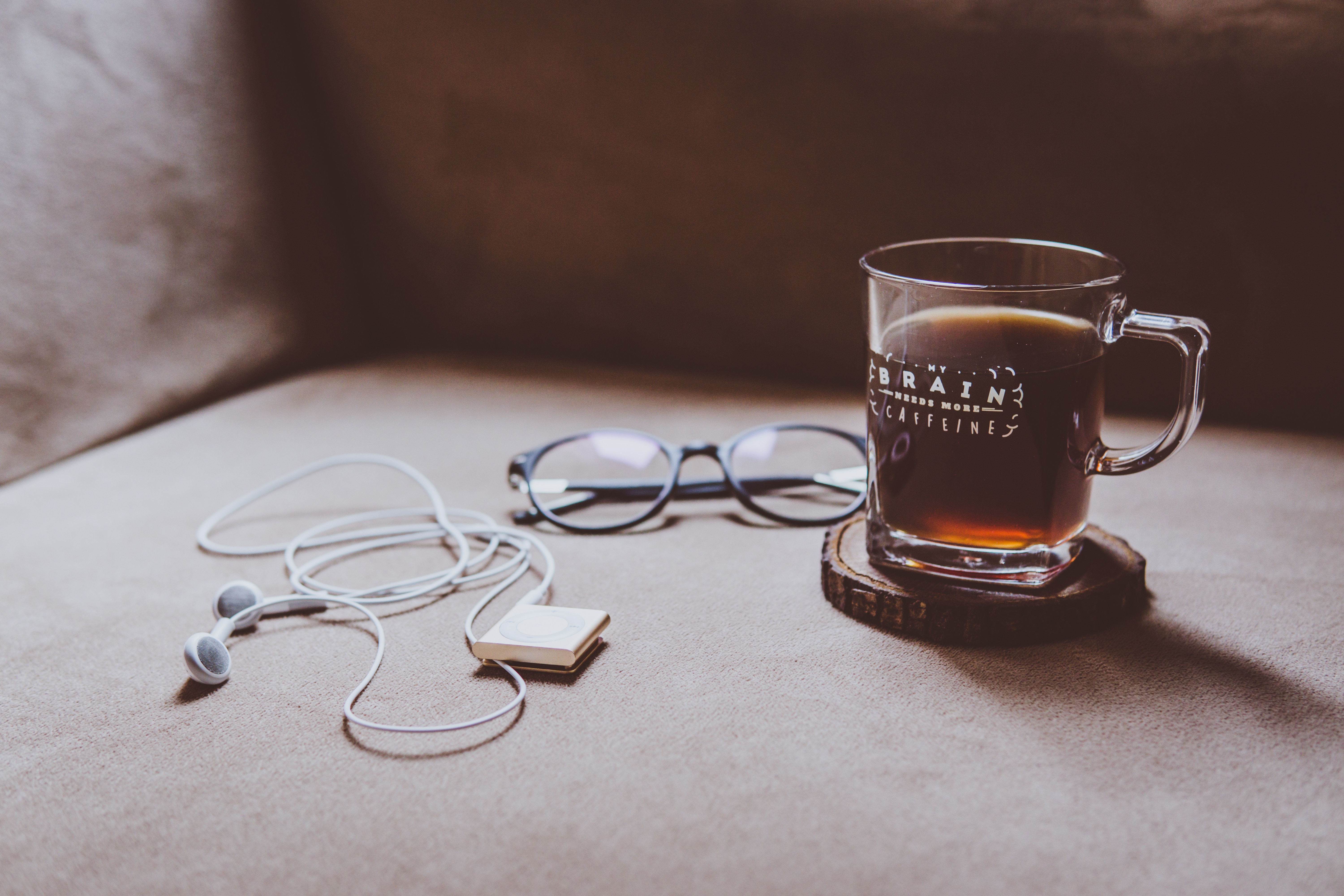 Coffee cup, headphones, and glasses on a couch HD Wallpaper