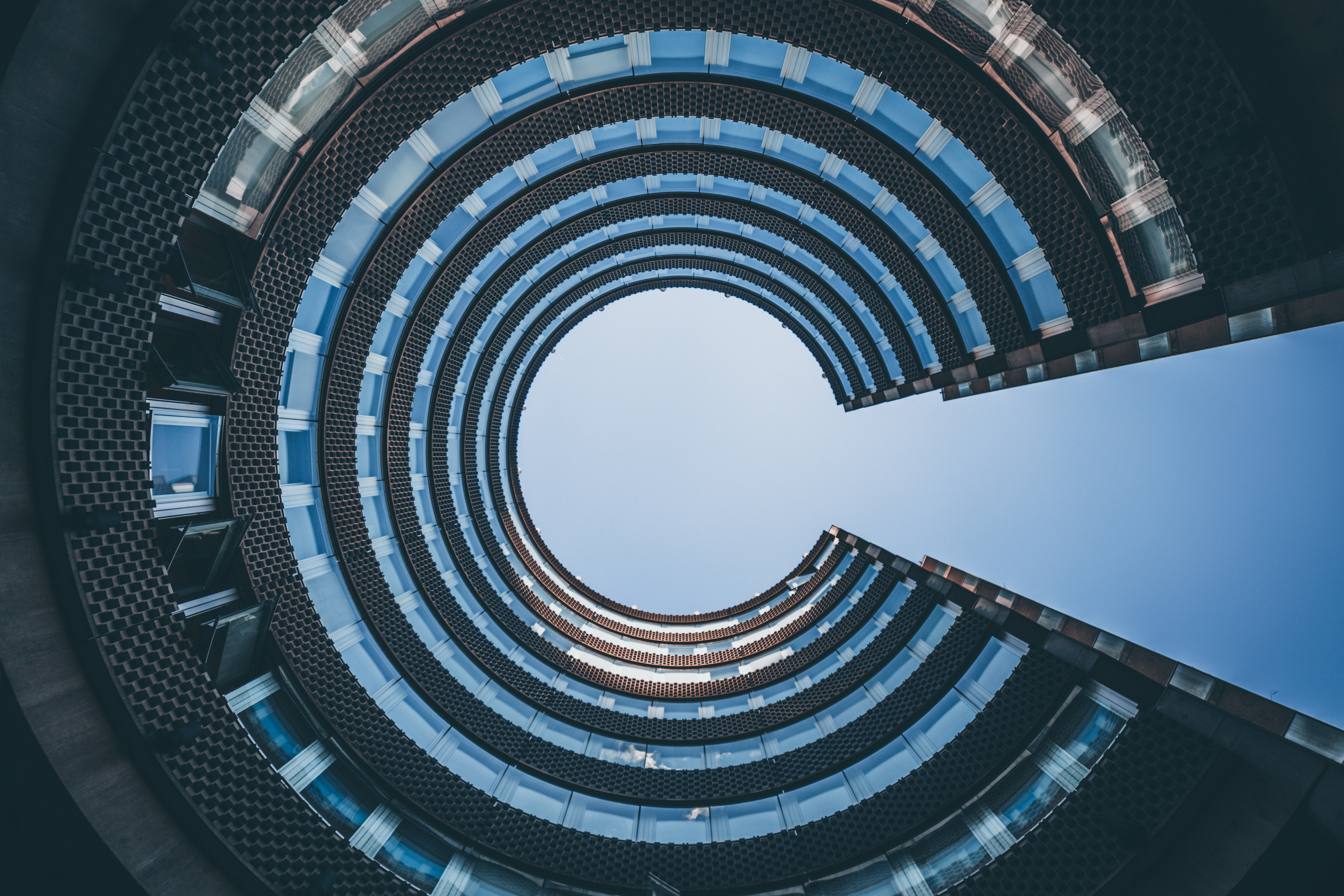 Looking up at a circular building with windows HD Wallpaper