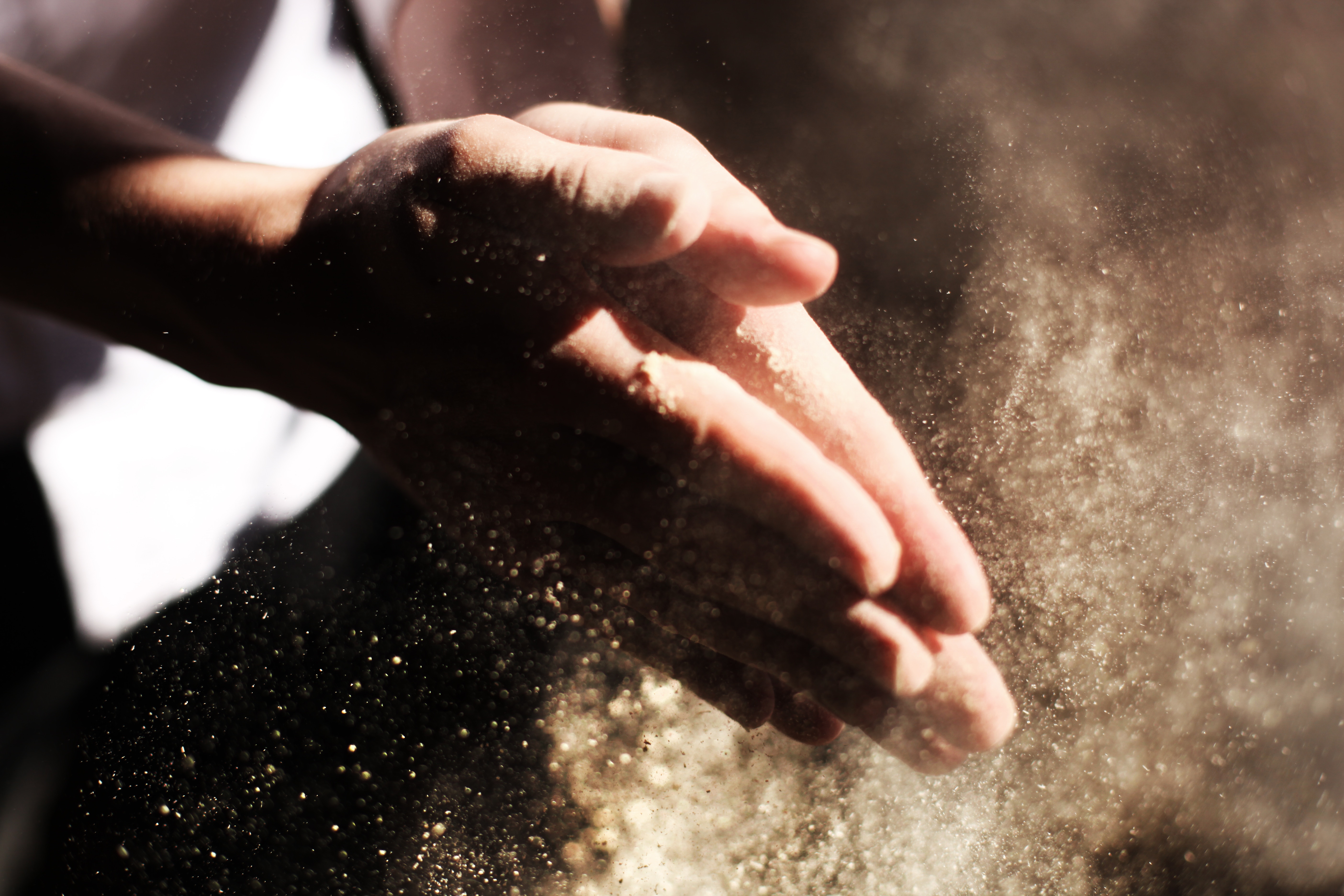 Hands shaking dust particles in sunlight HD Wallpaper