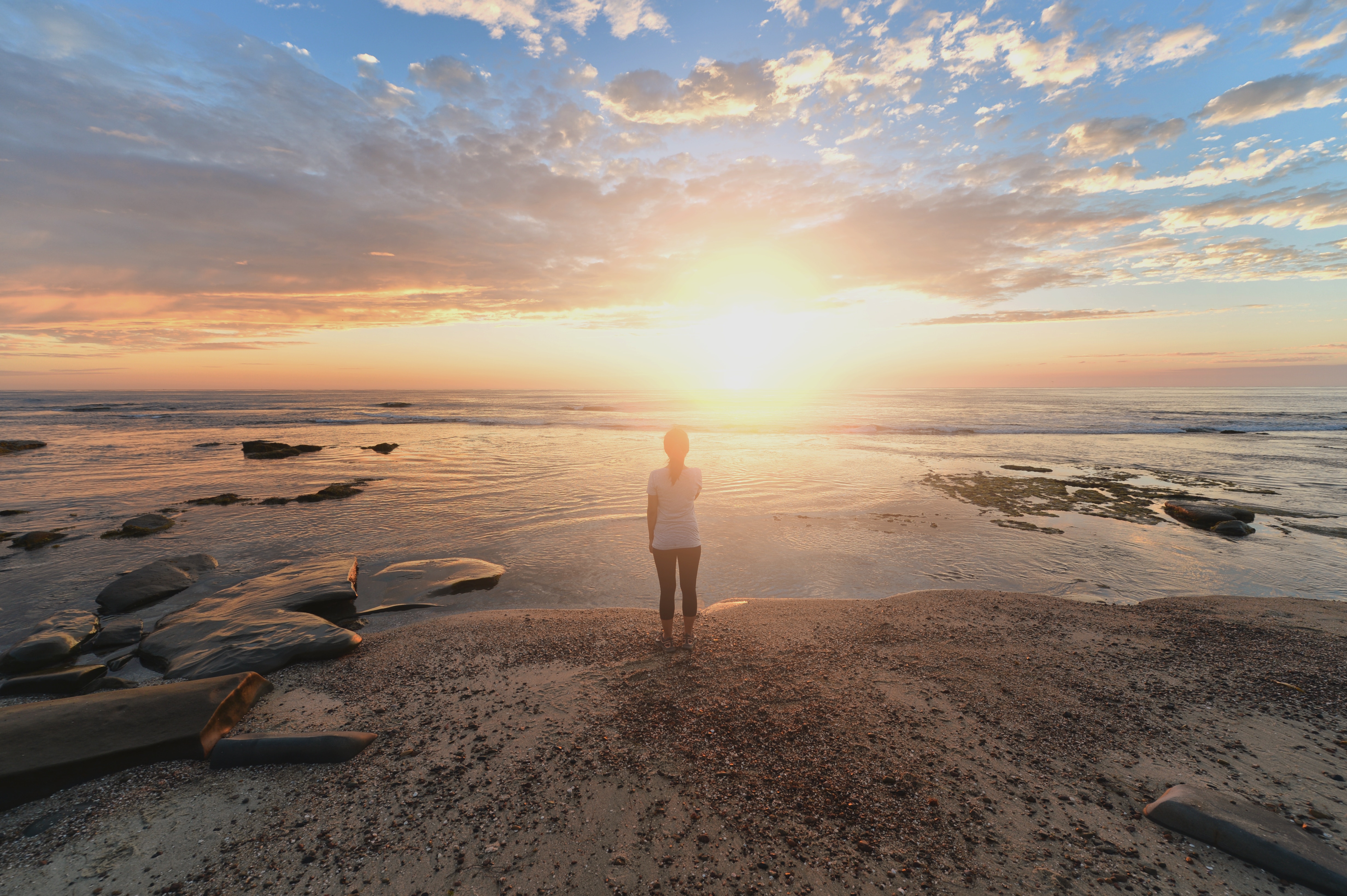 Woman standing on a beach at sunset HD Wallpaper