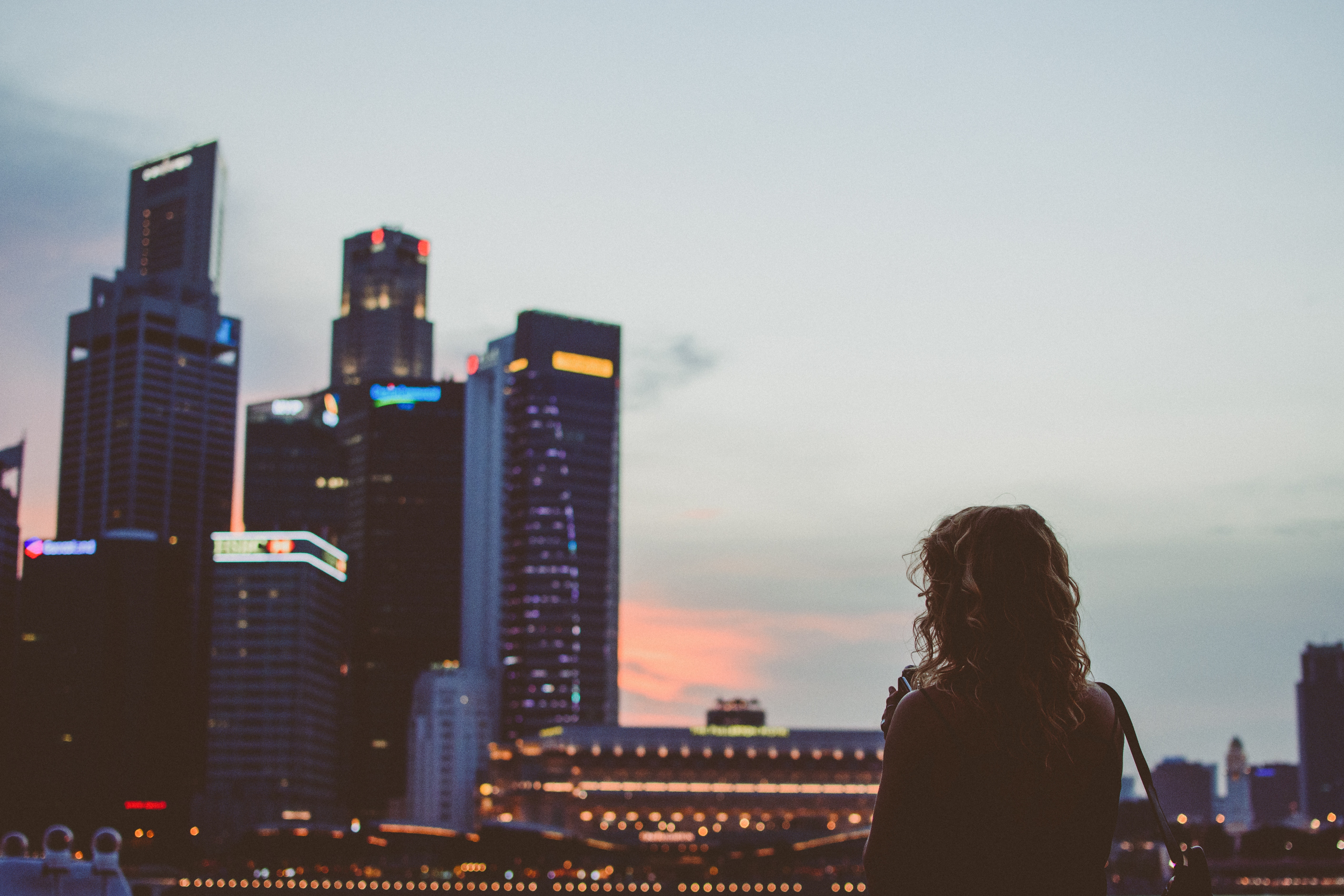 Woman looking at Singapore skyline at dusk HD Wallpaper