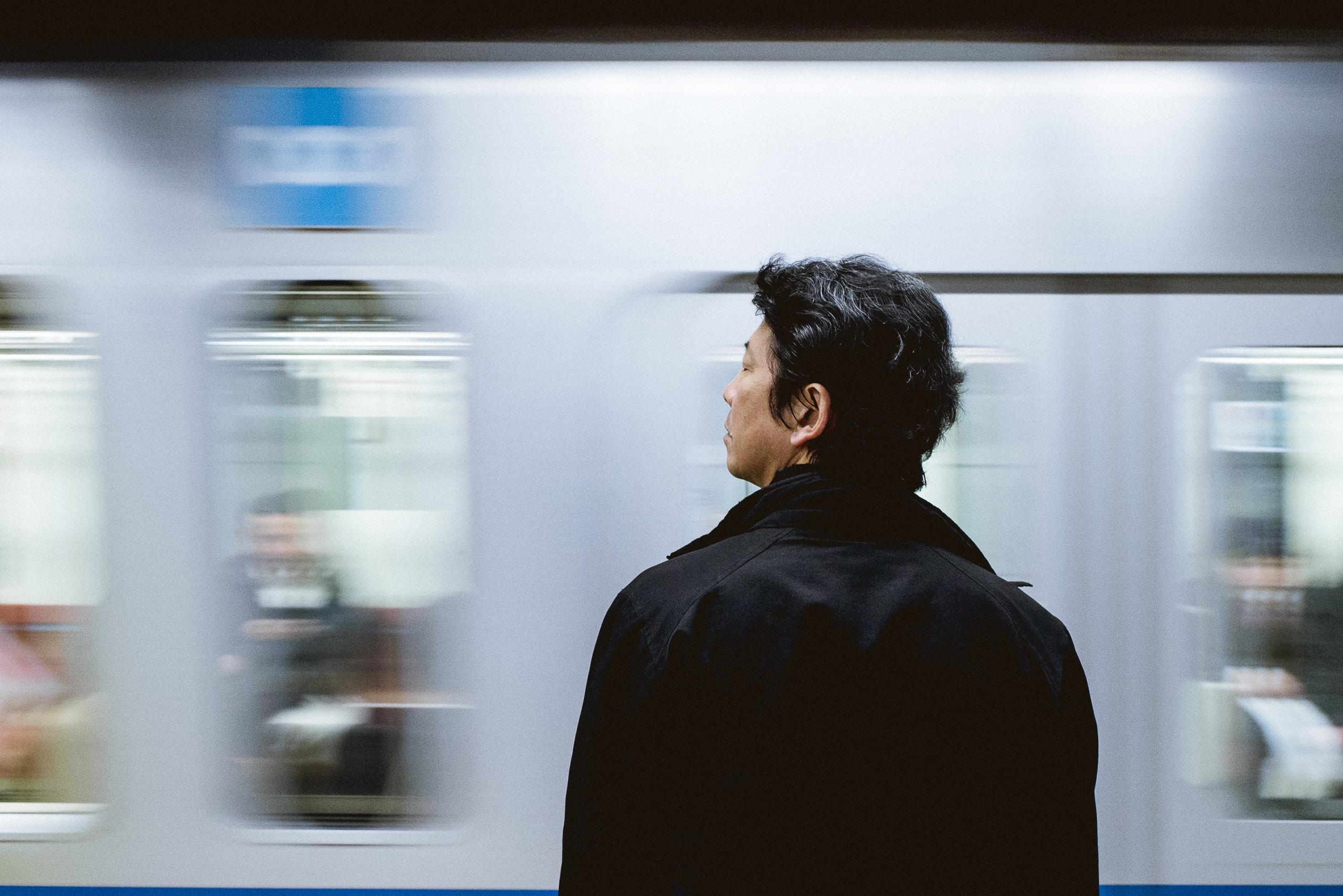Man in black coat waiting for a moving subway train HD Wallpaper