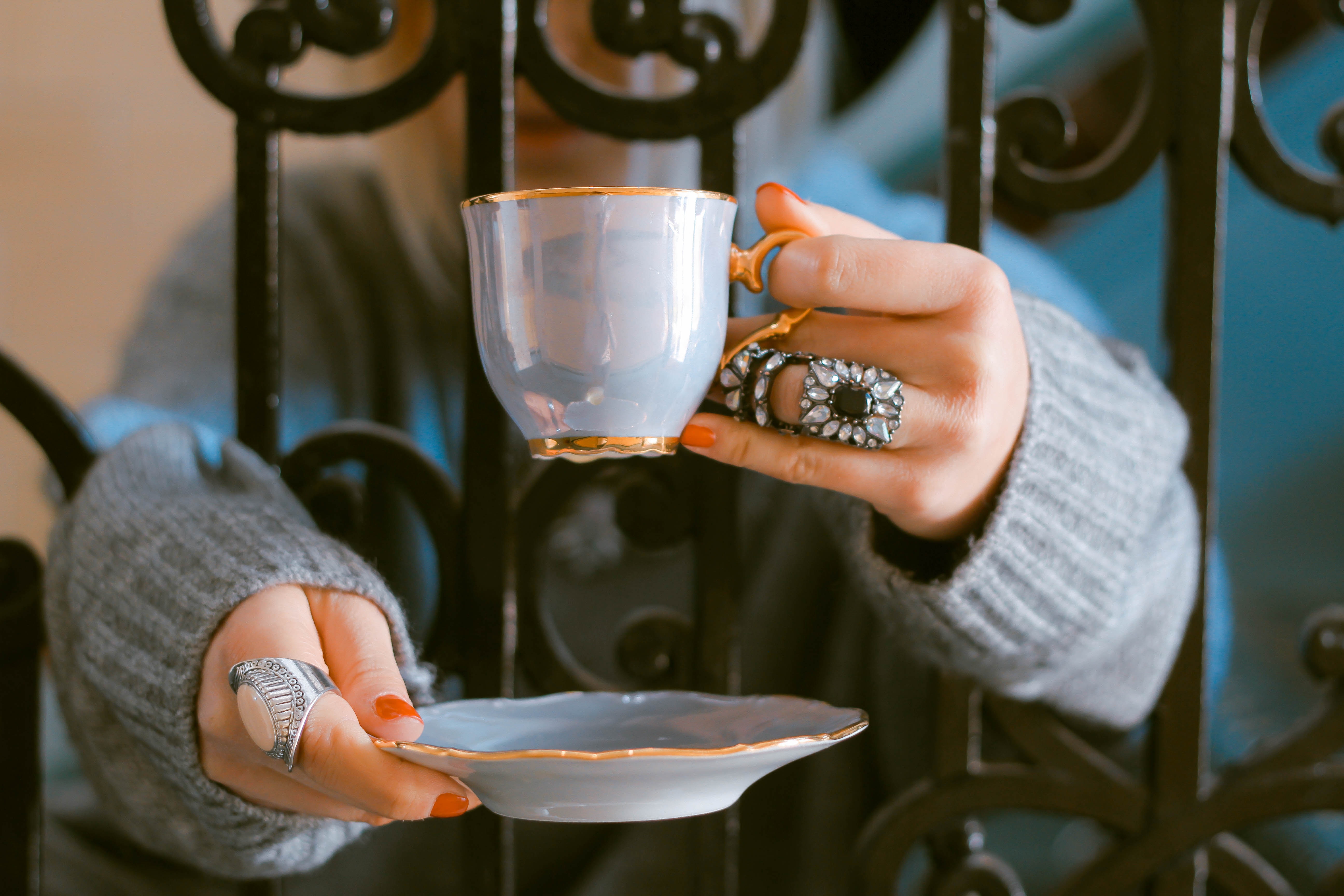 Woman holding a teacup and saucer with ornate rings HD Wallpaper