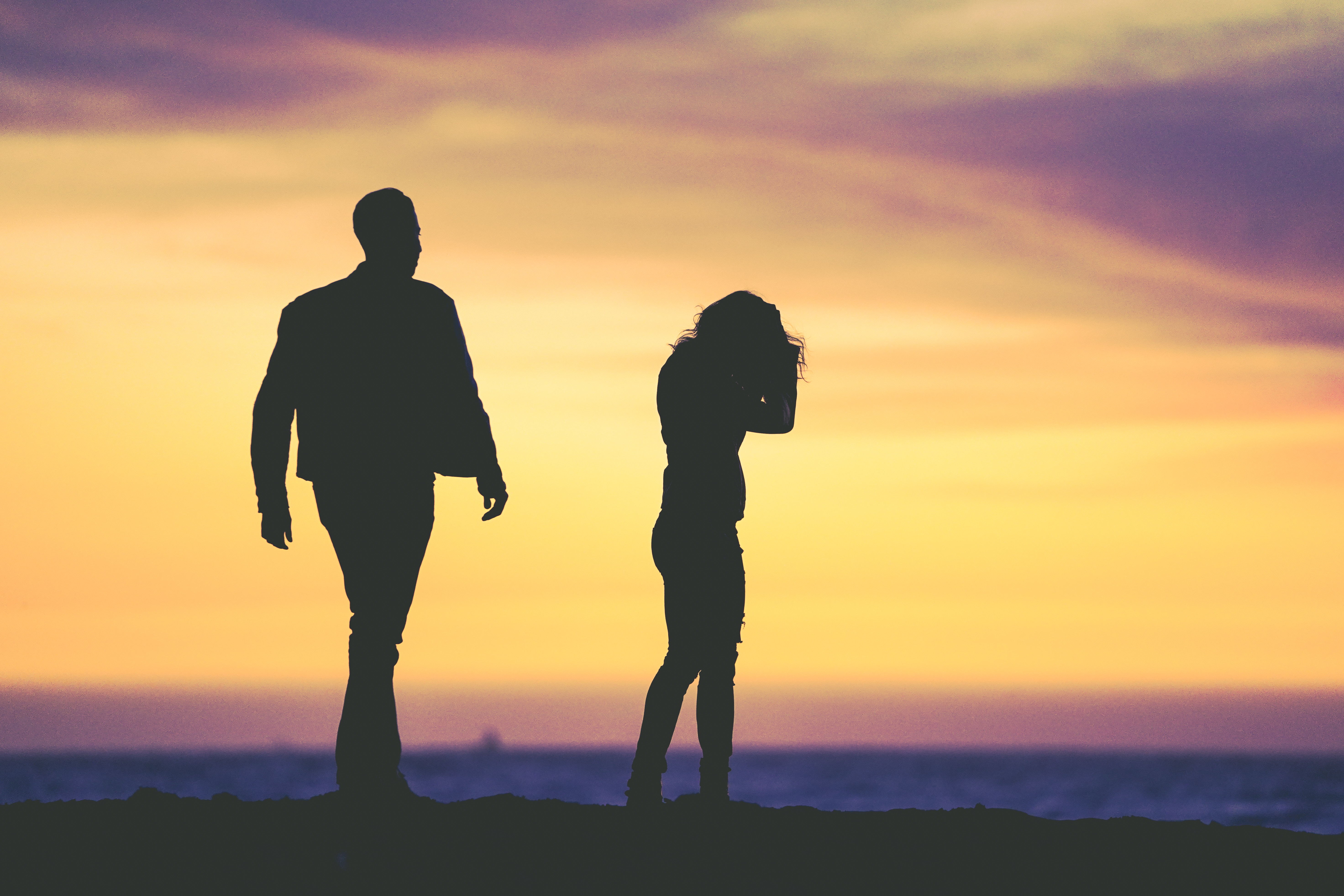 Man walks away from woman at sunset by the sea HD Wallpaper