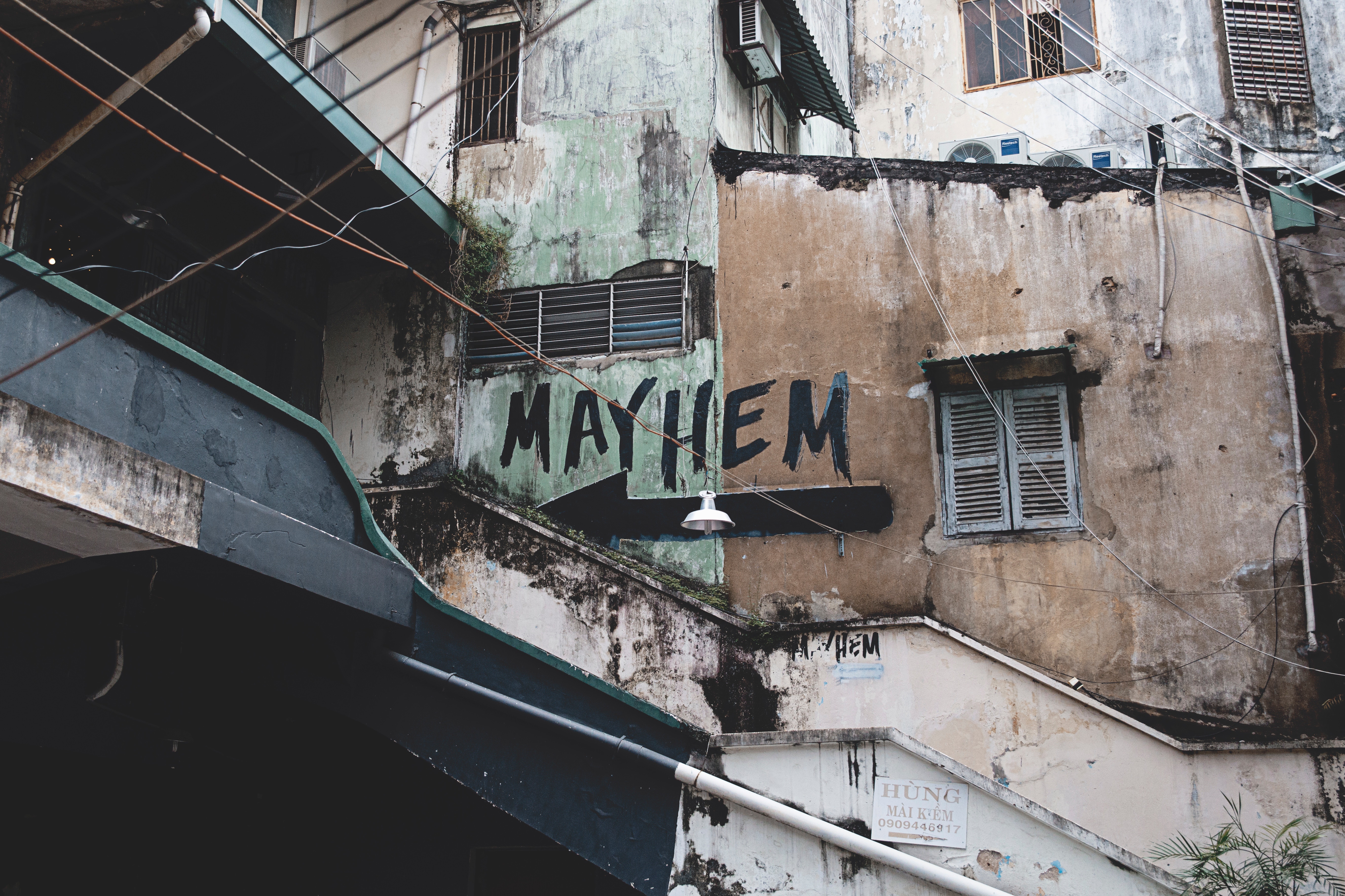 Graffiti art spelling "MAYHEM" on a weathered building exterior HD Wallpaper