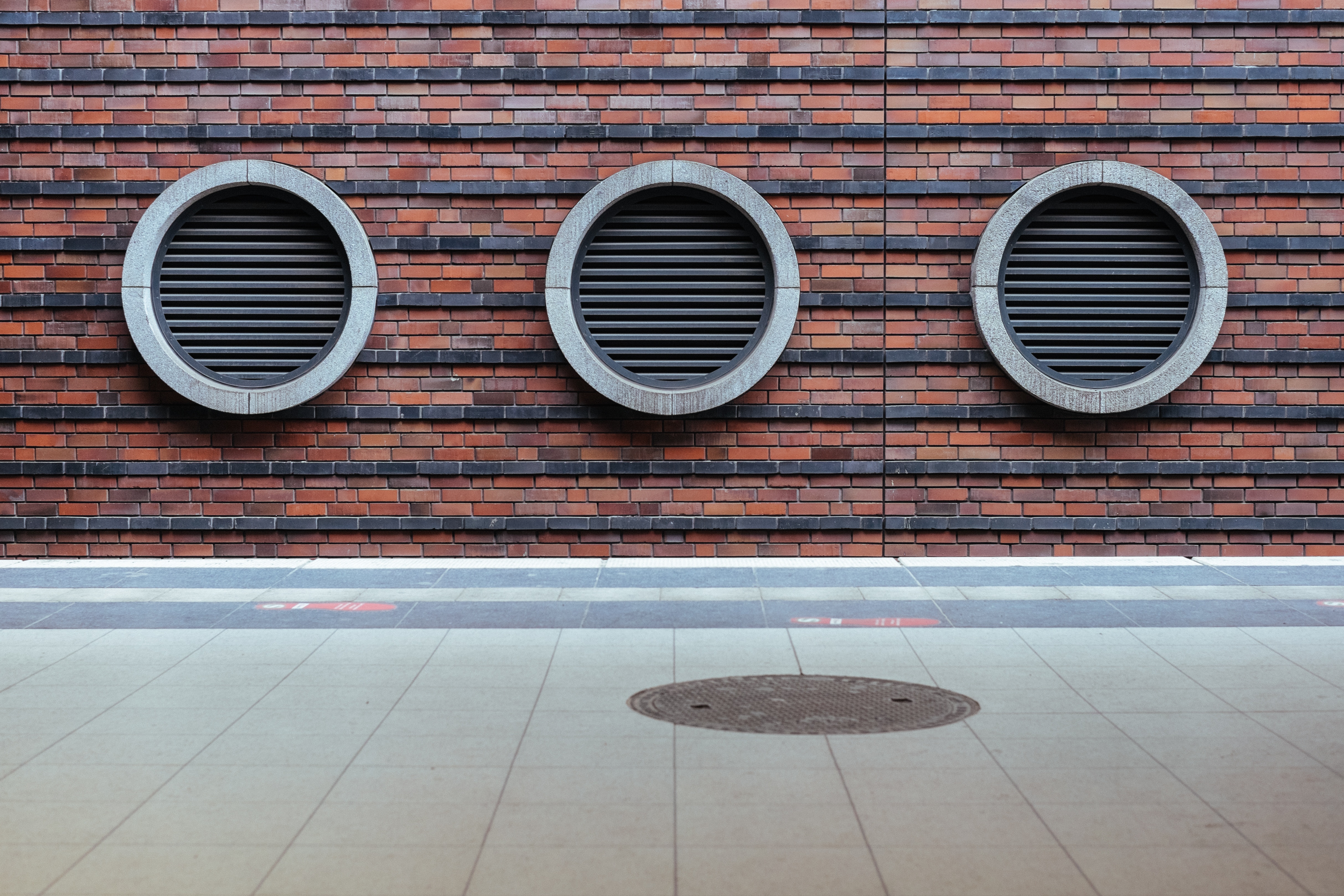 Three circular vents on a brick wall HD Wallpaper