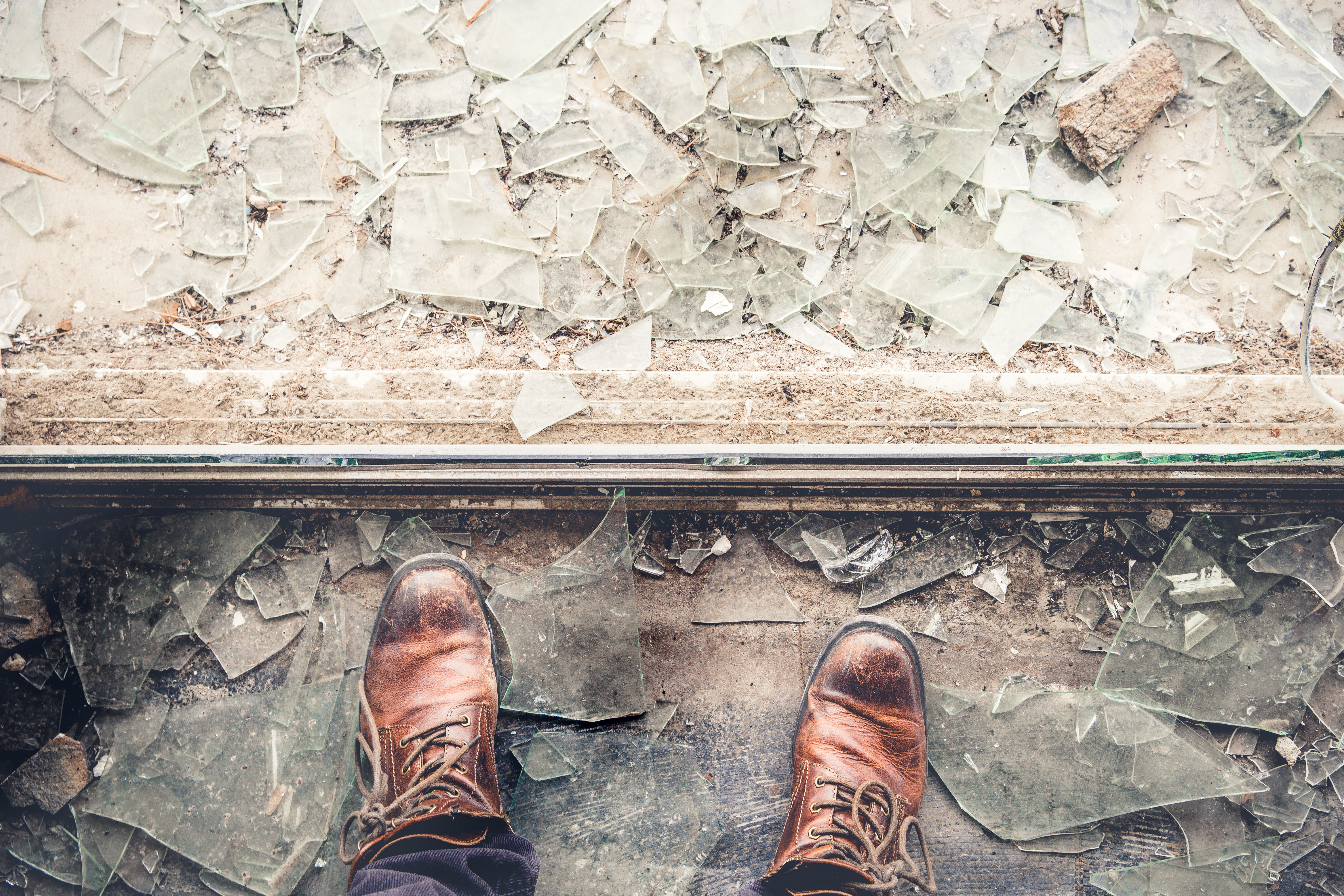 Brown leather boots standing on broken glass shards HD Wallpaper